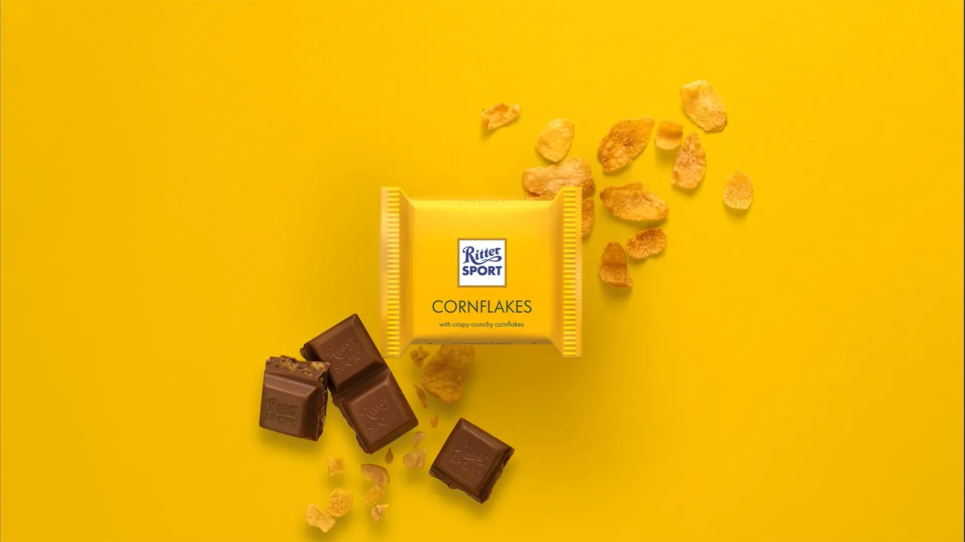 Ritter Sport chocolate bar packaging with cocoa beans, broken chocolate, and milk on a blue background.