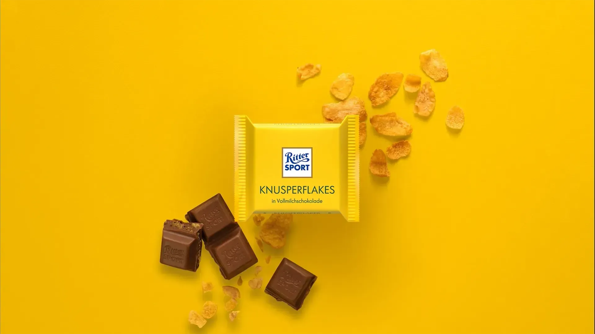 Verpackung einer blauen Schokoladentafel mit Nüssen, Schokoladenstückchen und dem Hinweis „55 % Kakaoanteil“ auf blauem Hintergrund