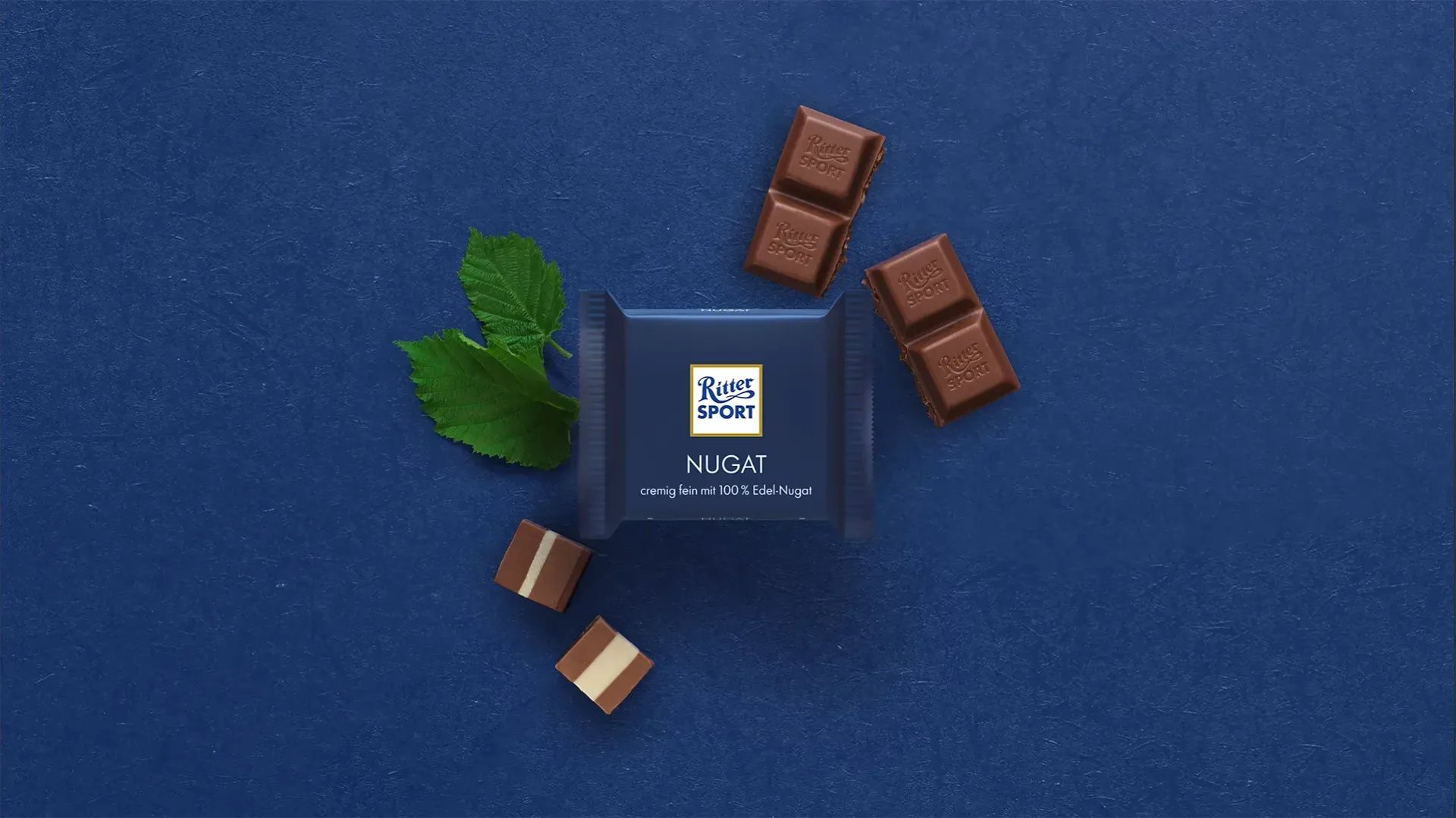 Verpackung einer blauen Schokoladentafel mit Nüssen, Schokoladenstückchen und dem Hinweis „55 % Kakaoanteil“ auf blauem Hintergrund