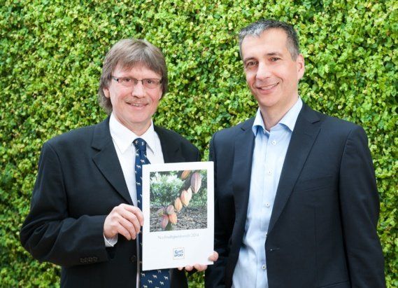 Two men standing next to each other holding a book