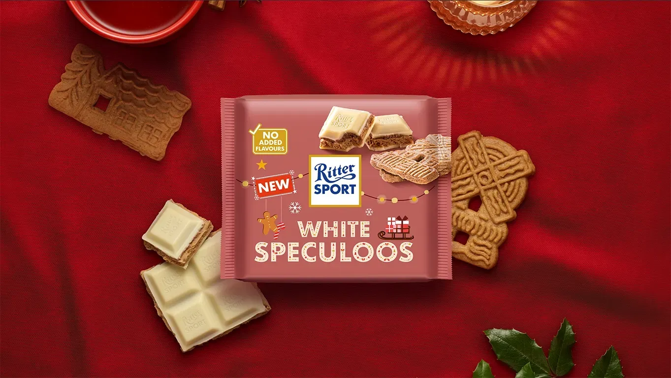 Ritter Sport chocolate bar packaging with cocoa beans, broken chocolate, and milk on a blue background.