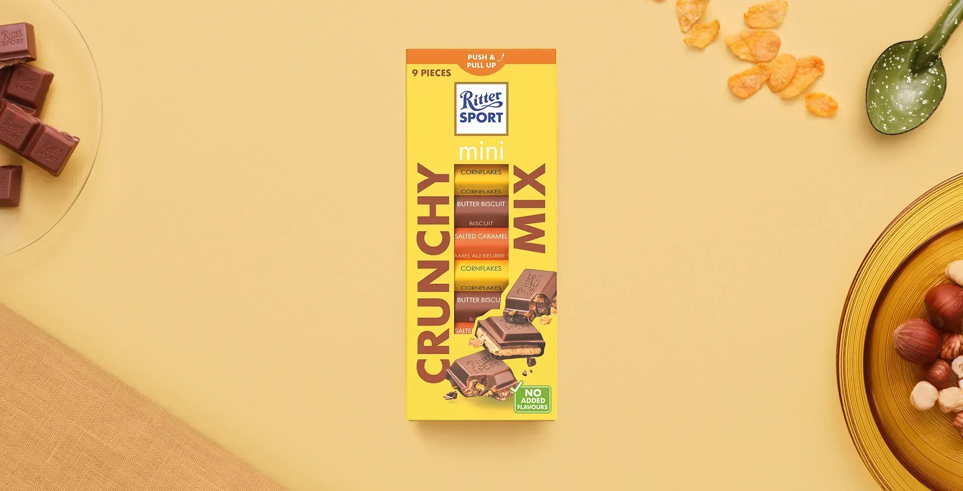 Ritter Sport chocolate bar packaging with cocoa beans, broken chocolate, and milk on a blue background.