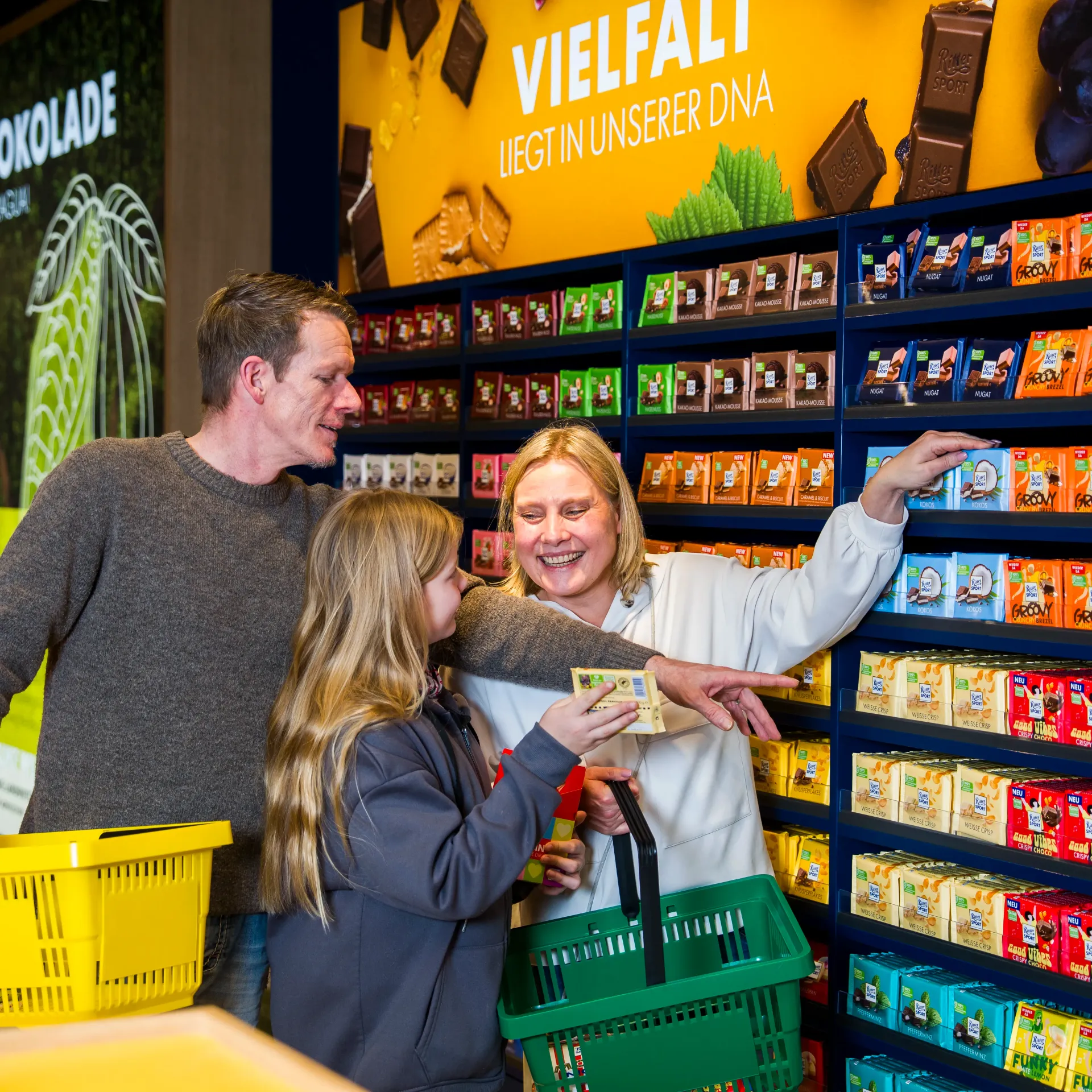 Familie legt Schokolade lachend in einen Einkaufskorb
