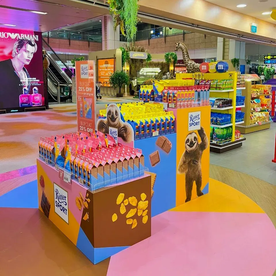 Display of Ritter Sport chocolate bars in a store, with colorful branding, a sloth graphic, and an advertisement for chocolate