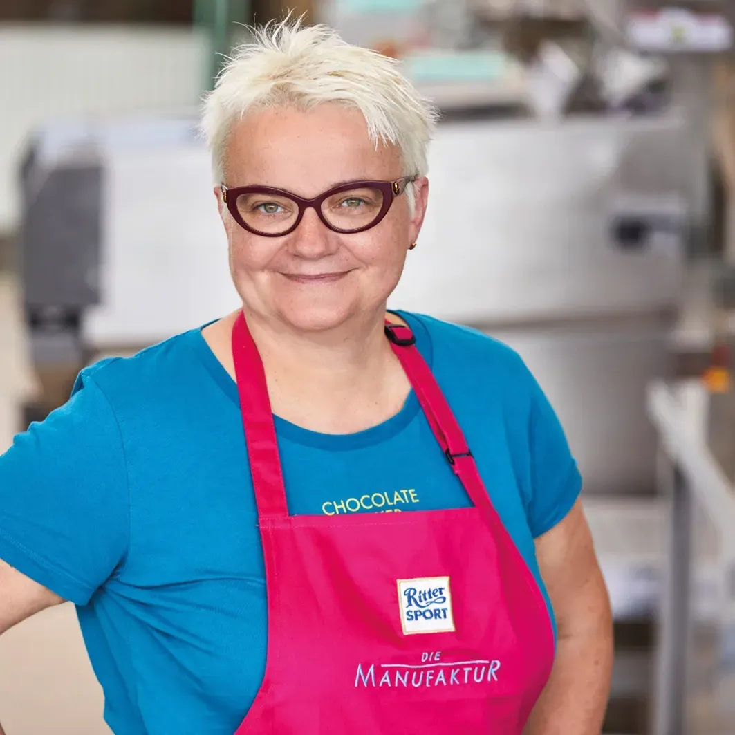 A woman wearing a pink apron that says Ritter Sport on it