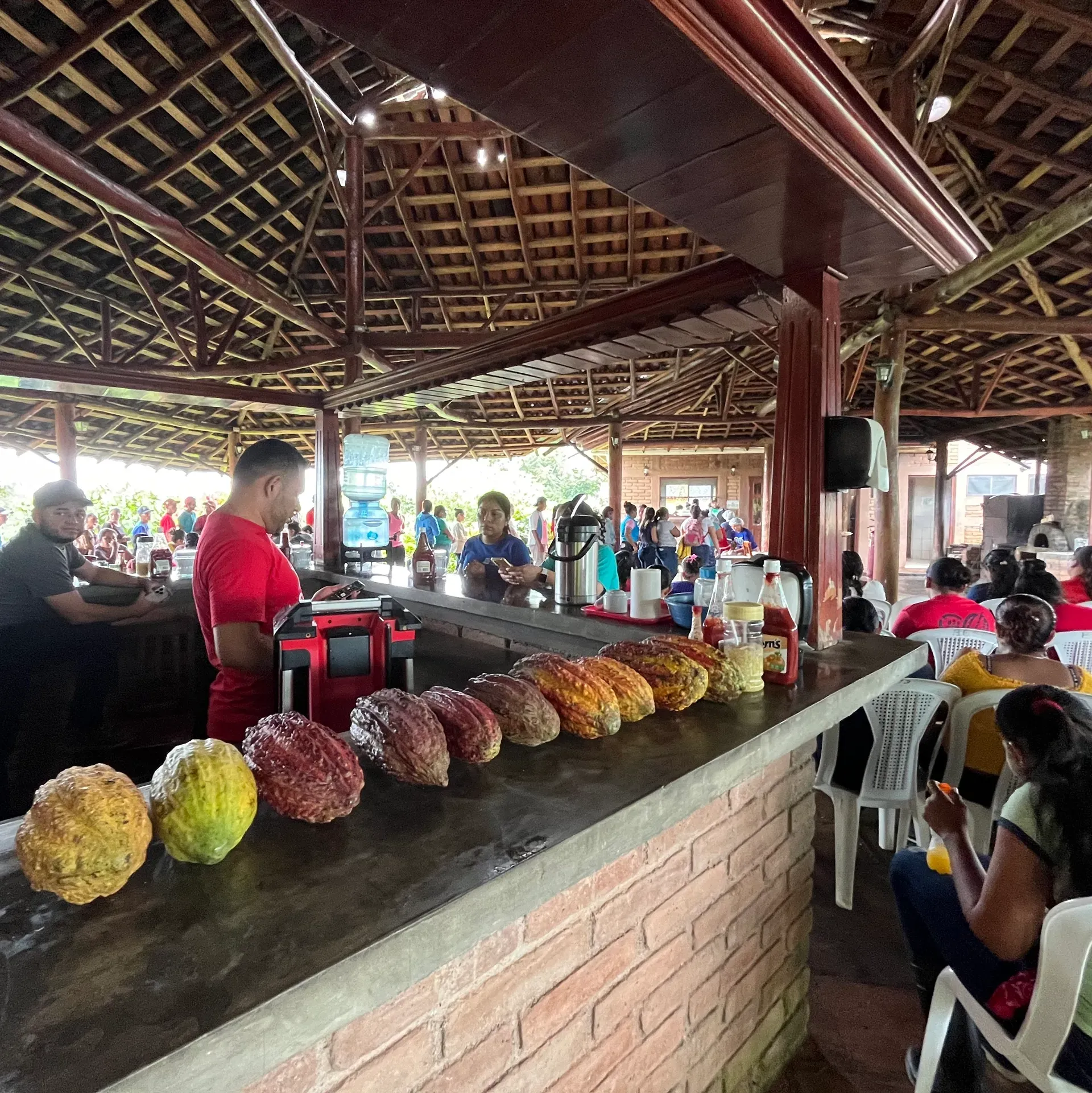 A man in a red shirt stands behind a counter with fruits on it