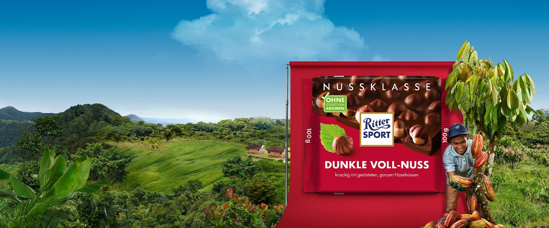 Schokoladentafelverpackung der Dunklen Vollnuss vor einer Landschaft aus Bergen und Kakaobäumen.