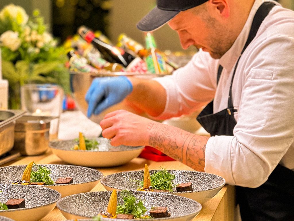 Ein Mann bereitet Essen in Schüsseln auf einem Tisch zu.