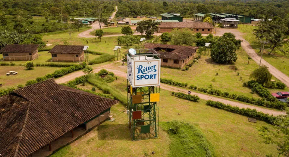 Aerial view of a resort with buildings, trees, and a RITTER SPORT sign on a water tower.