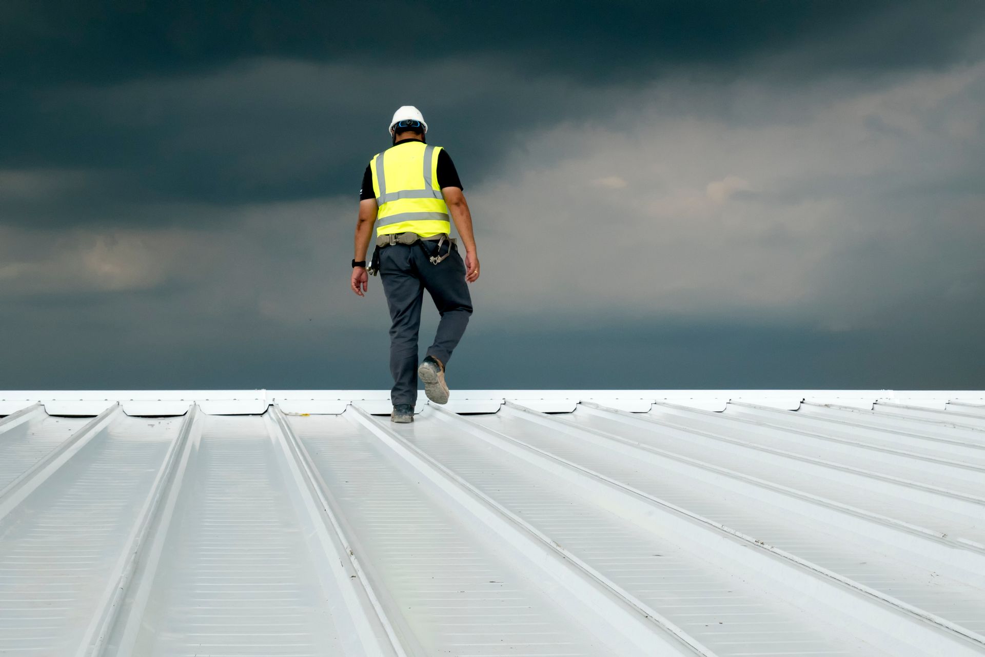 A man is walking on top of a white roof.
