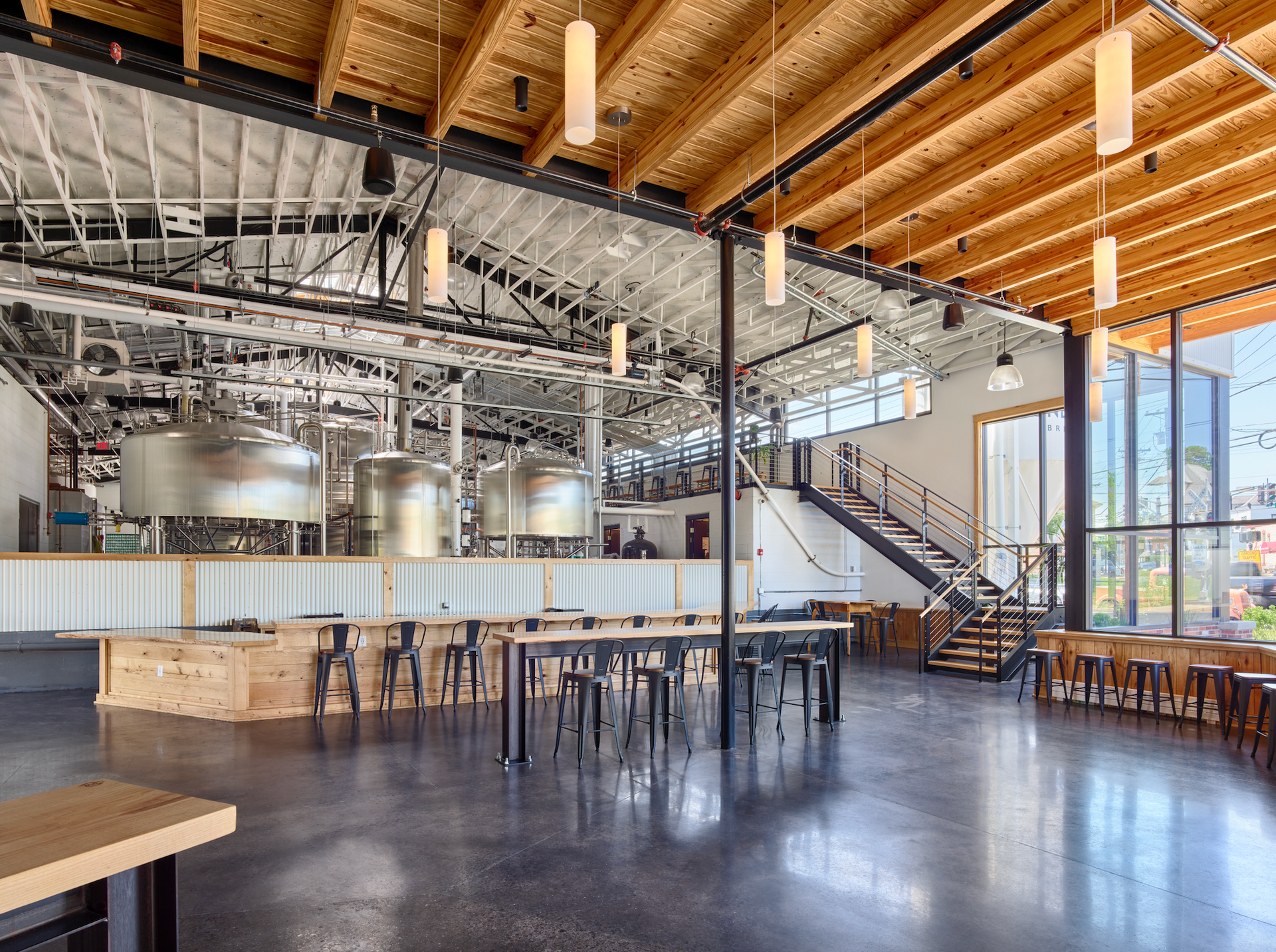 Brewery interior with brewing tanks, bar seating, and large windows.