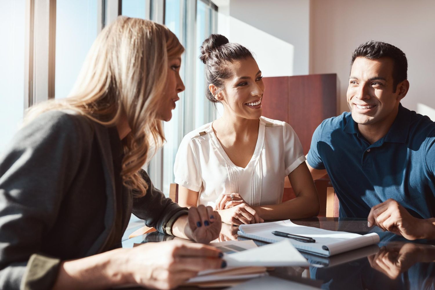 A group of people are sitting around a table talking to each other.