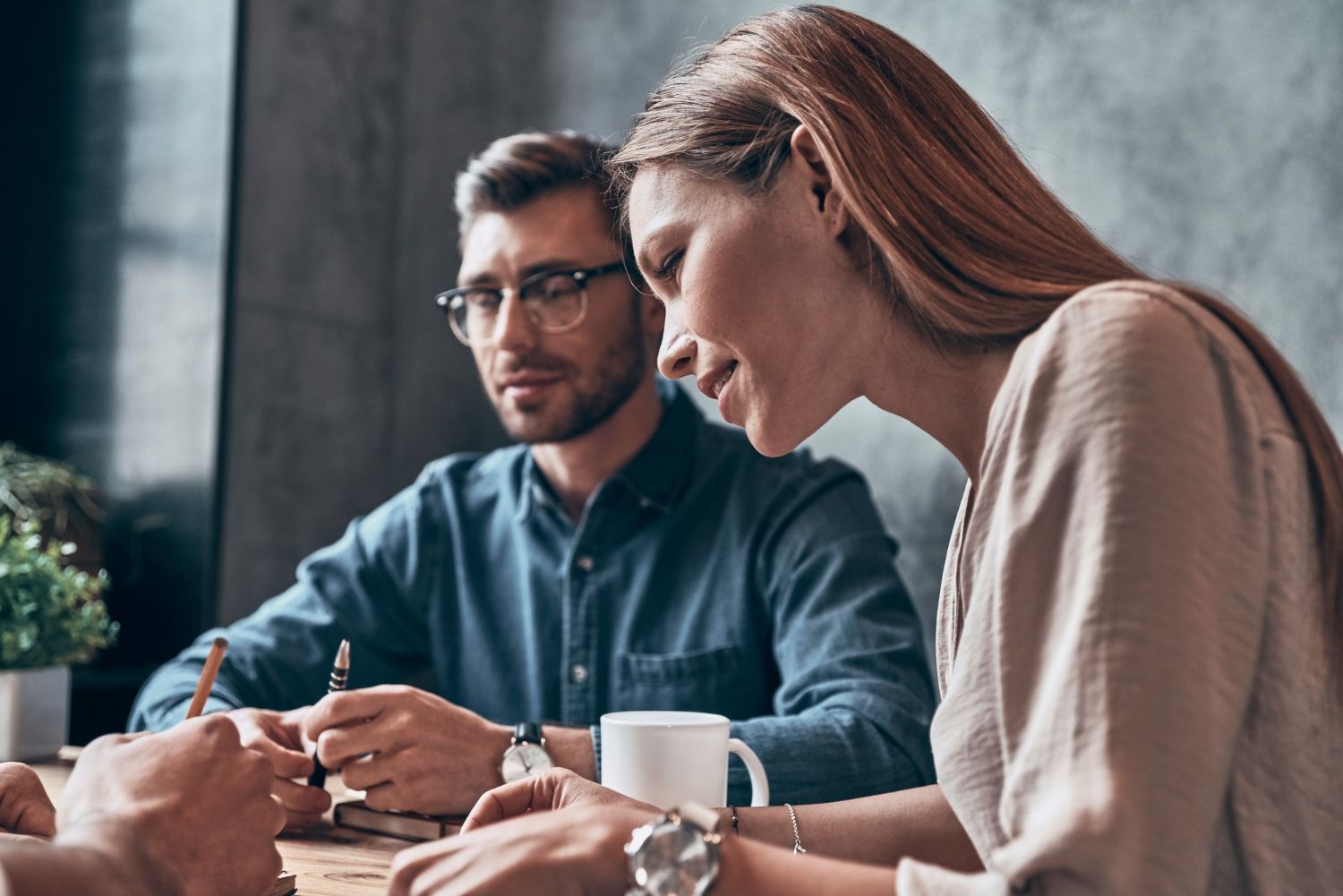 A man and a woman are sitting at a table with a cup of coffee.