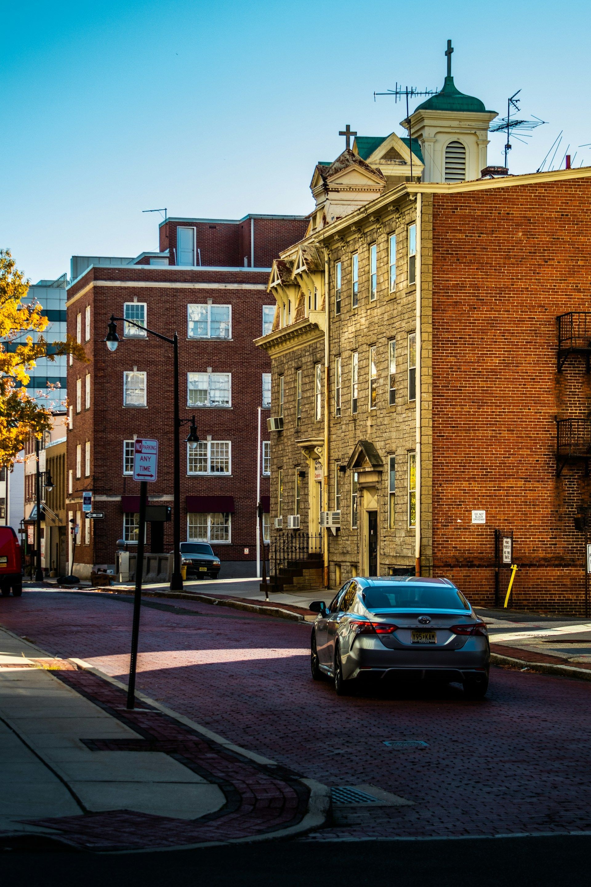 A car is driving down a street in front of a brick building