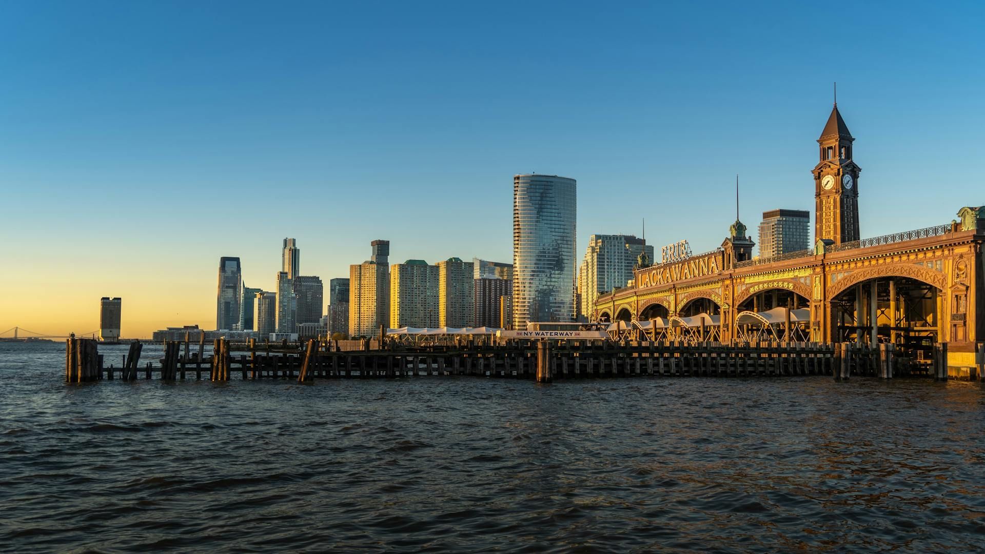 A pier with a city skyline in the background and a clock tower in the foreground.