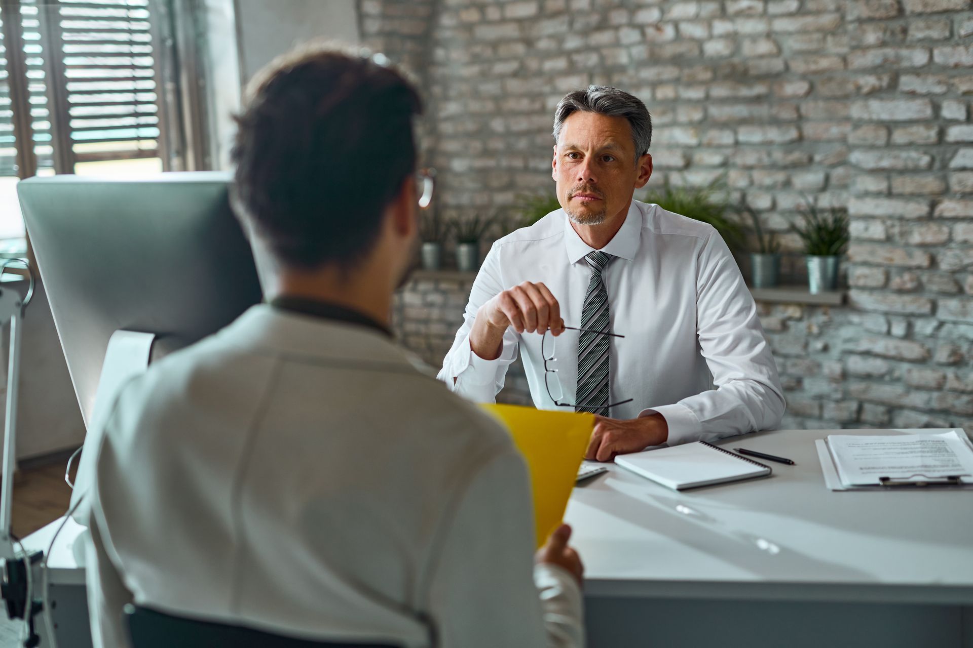 Man interviewing a job candidate at a desk in an office.