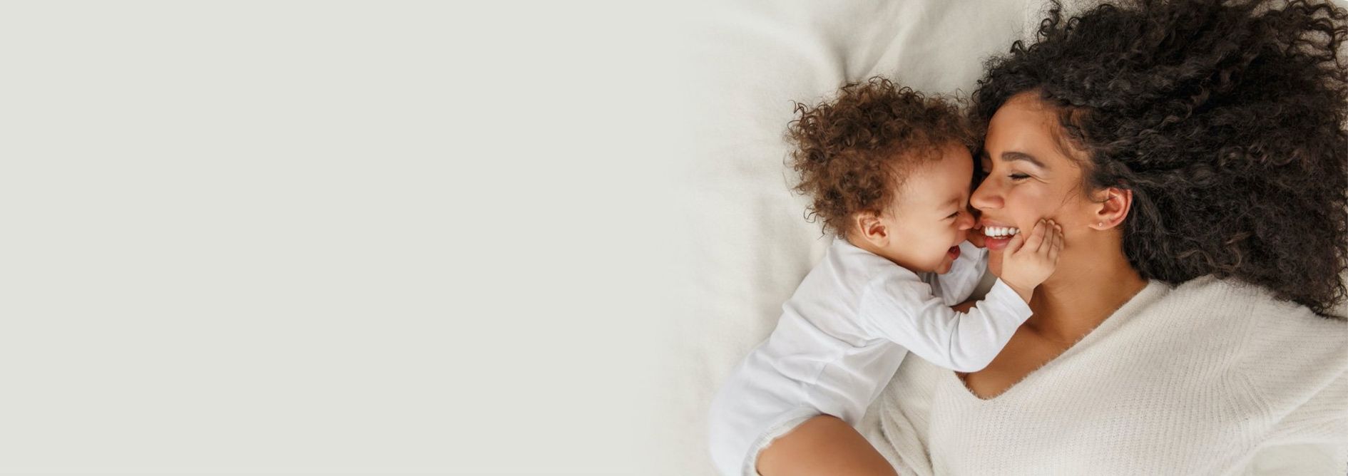 A woman is laying on a bed holding a baby.