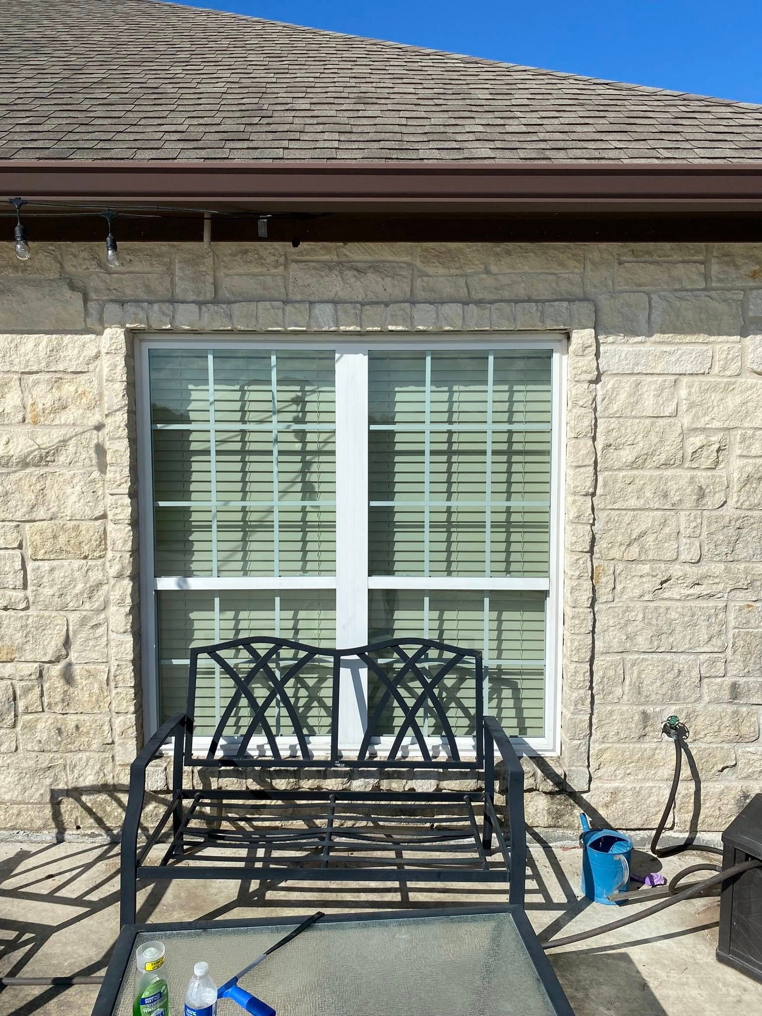 A brick house with a bench in front of a window.