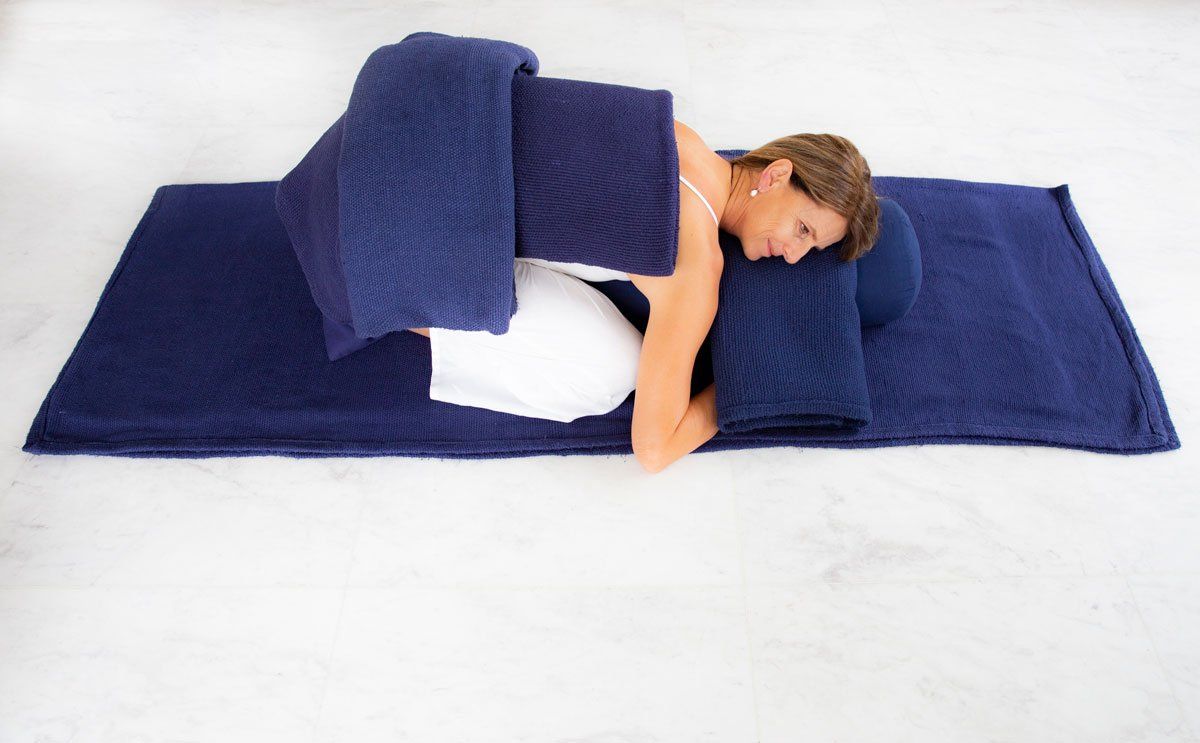 A woman is laying on a blue blanket on the floor