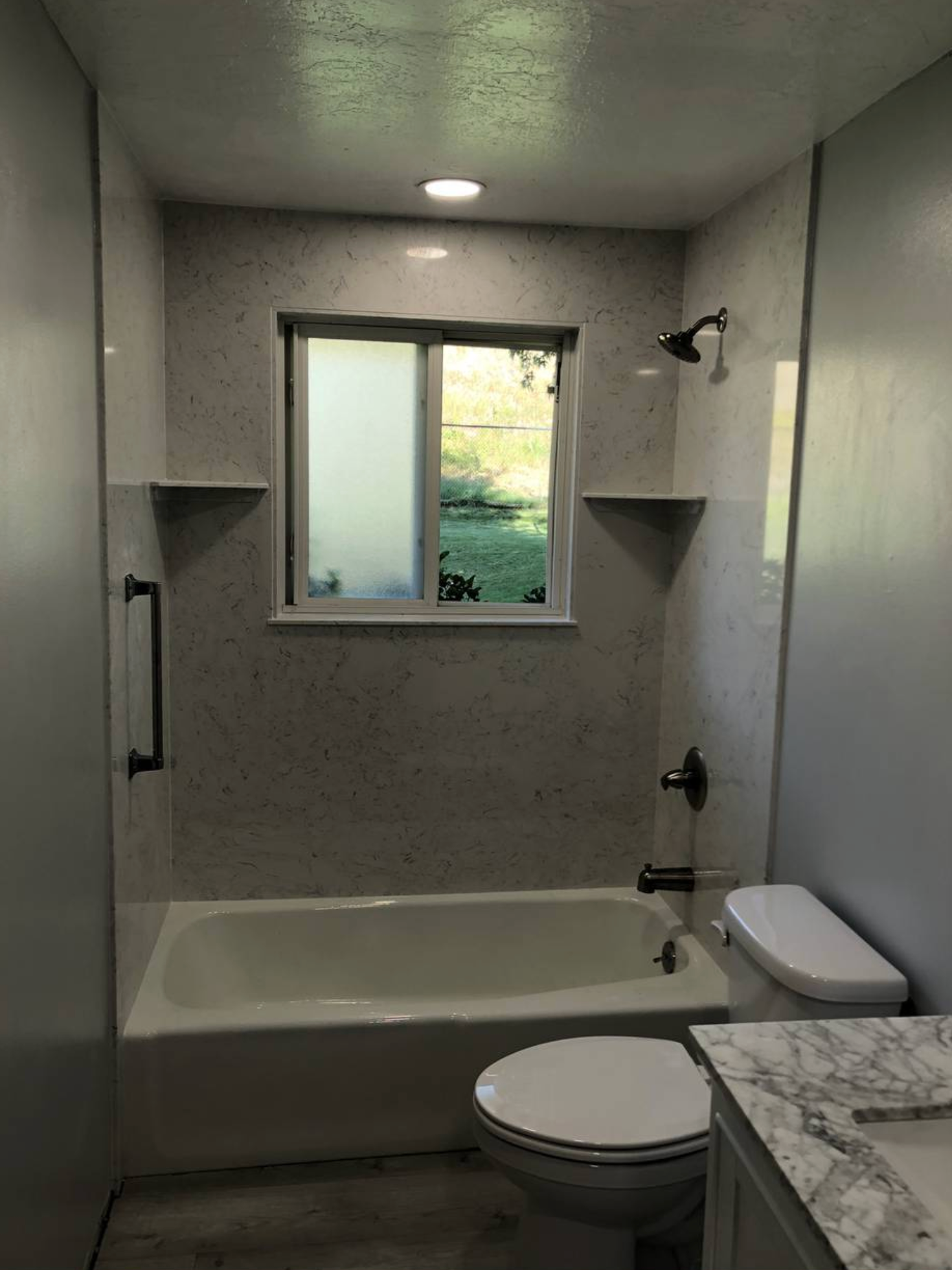 A bathroom with a tub , toilet , sink and window.