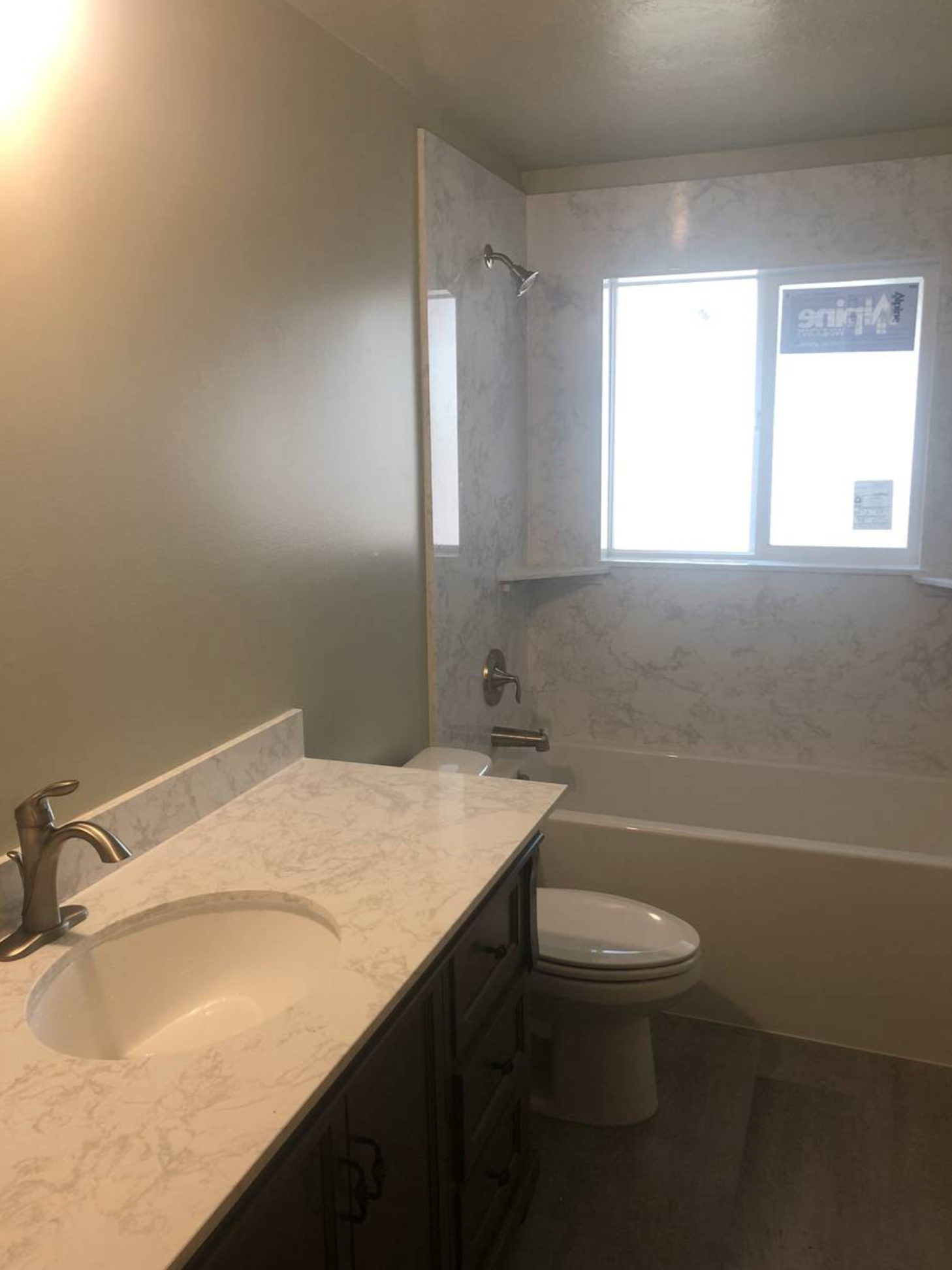 A bathroom with a sink , toilet , tub and window.