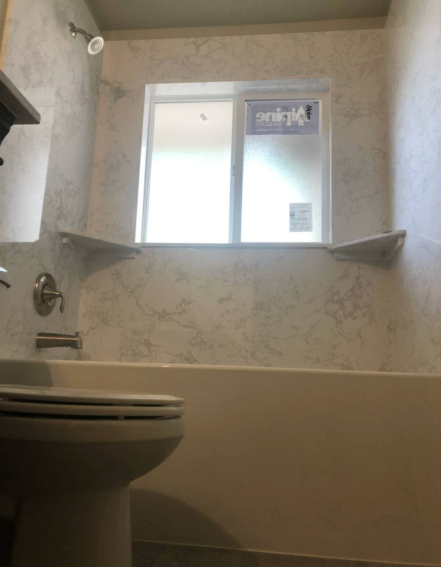 A bathroom with a tub , toilet , sink and window.