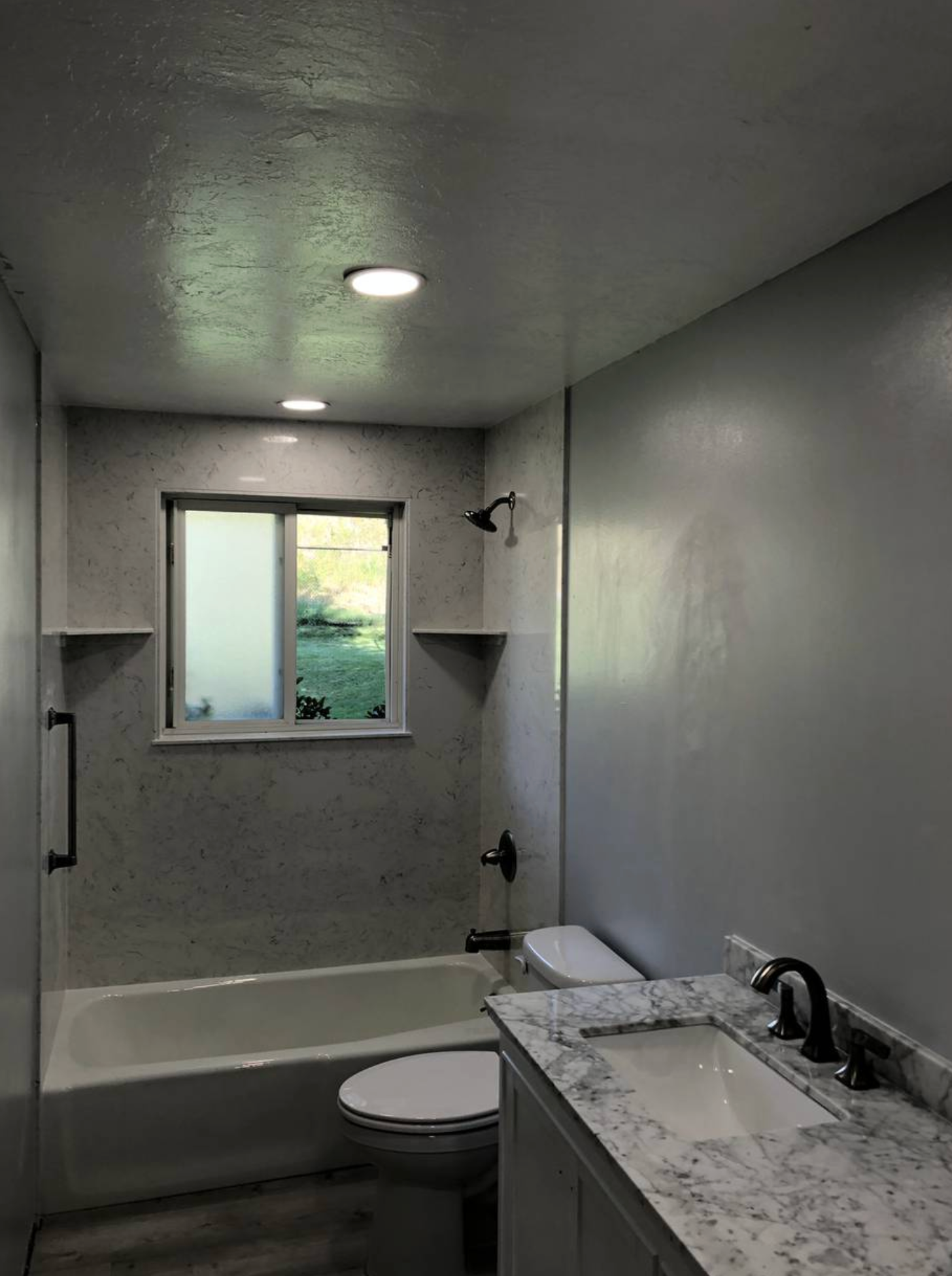 A bathroom with a sink , toilet , bathtub and window.