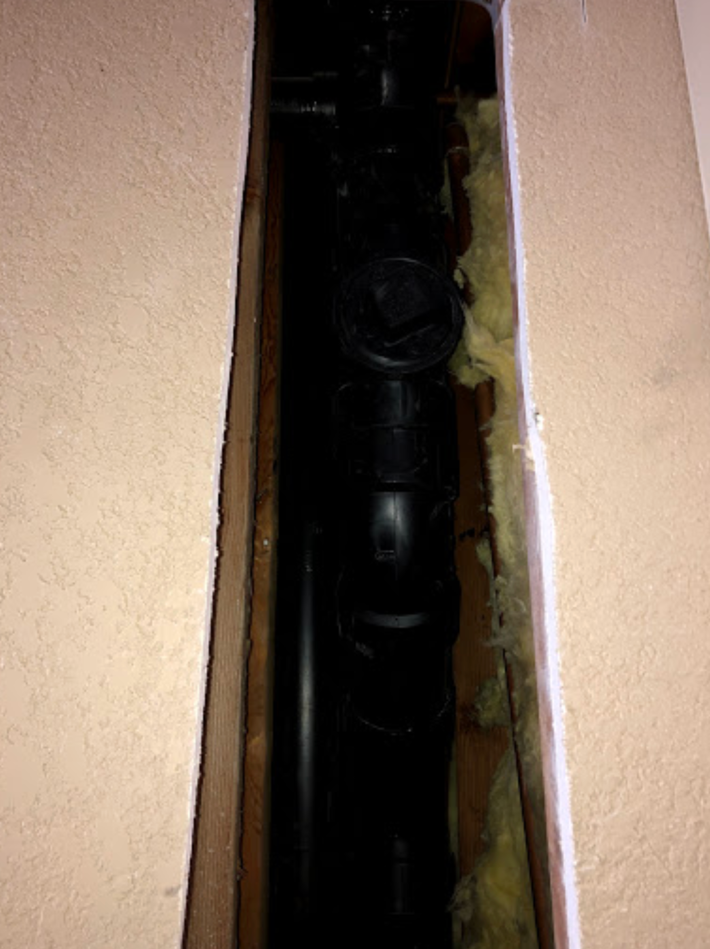 A black pipe is coming out of a hole in a wall.