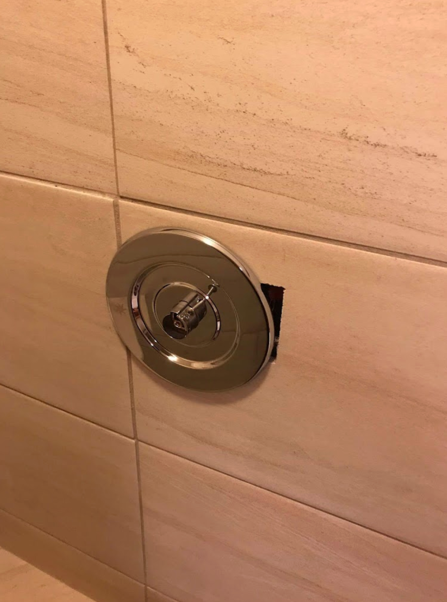 A close up of a shower head on a tiled wall.