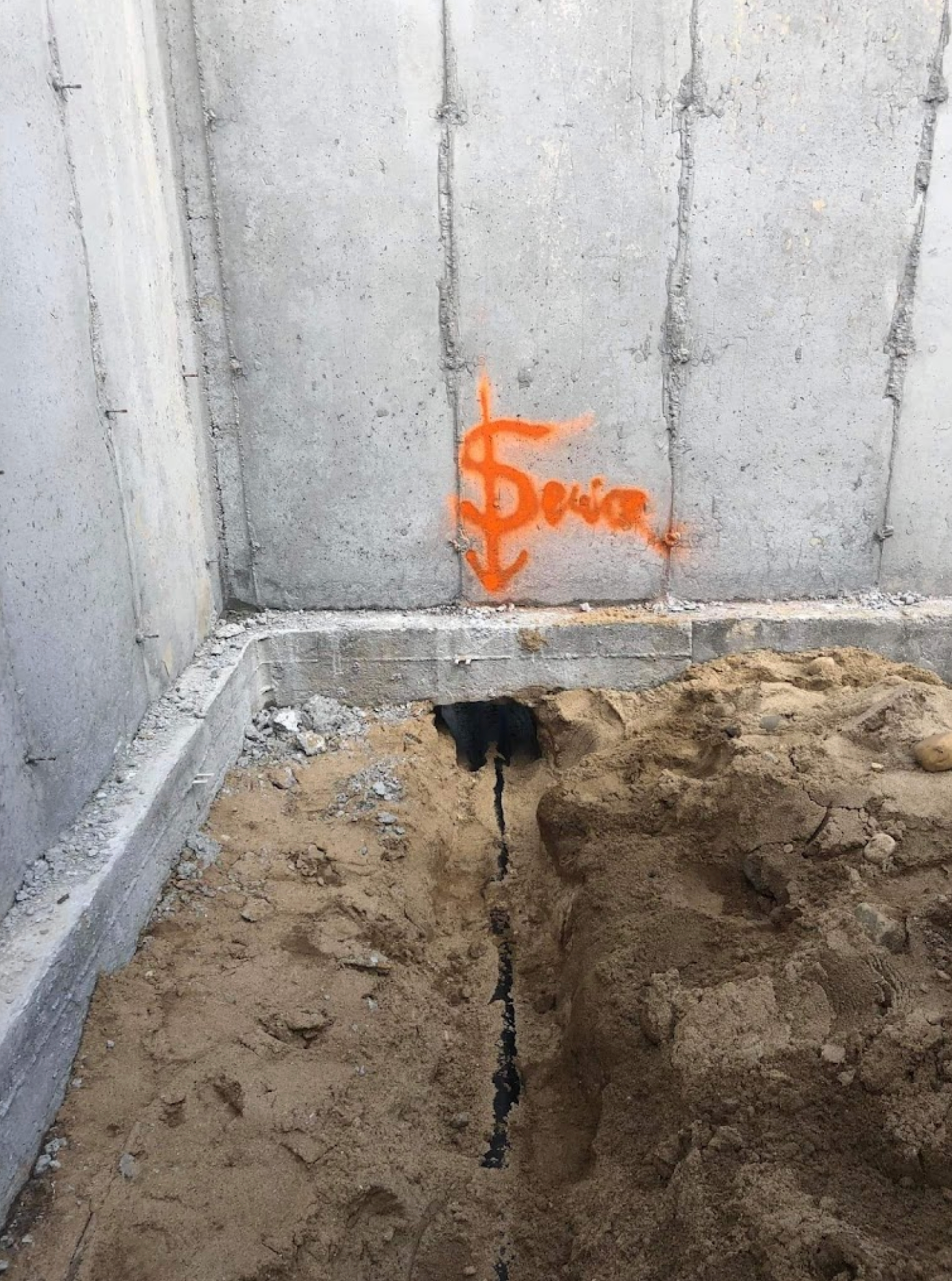 A concrete wall with a dollar sign painted on it.