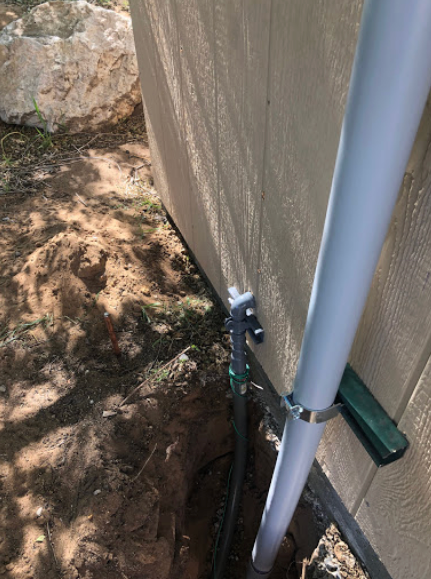 A white pipe is sitting in the dirt next to a building.