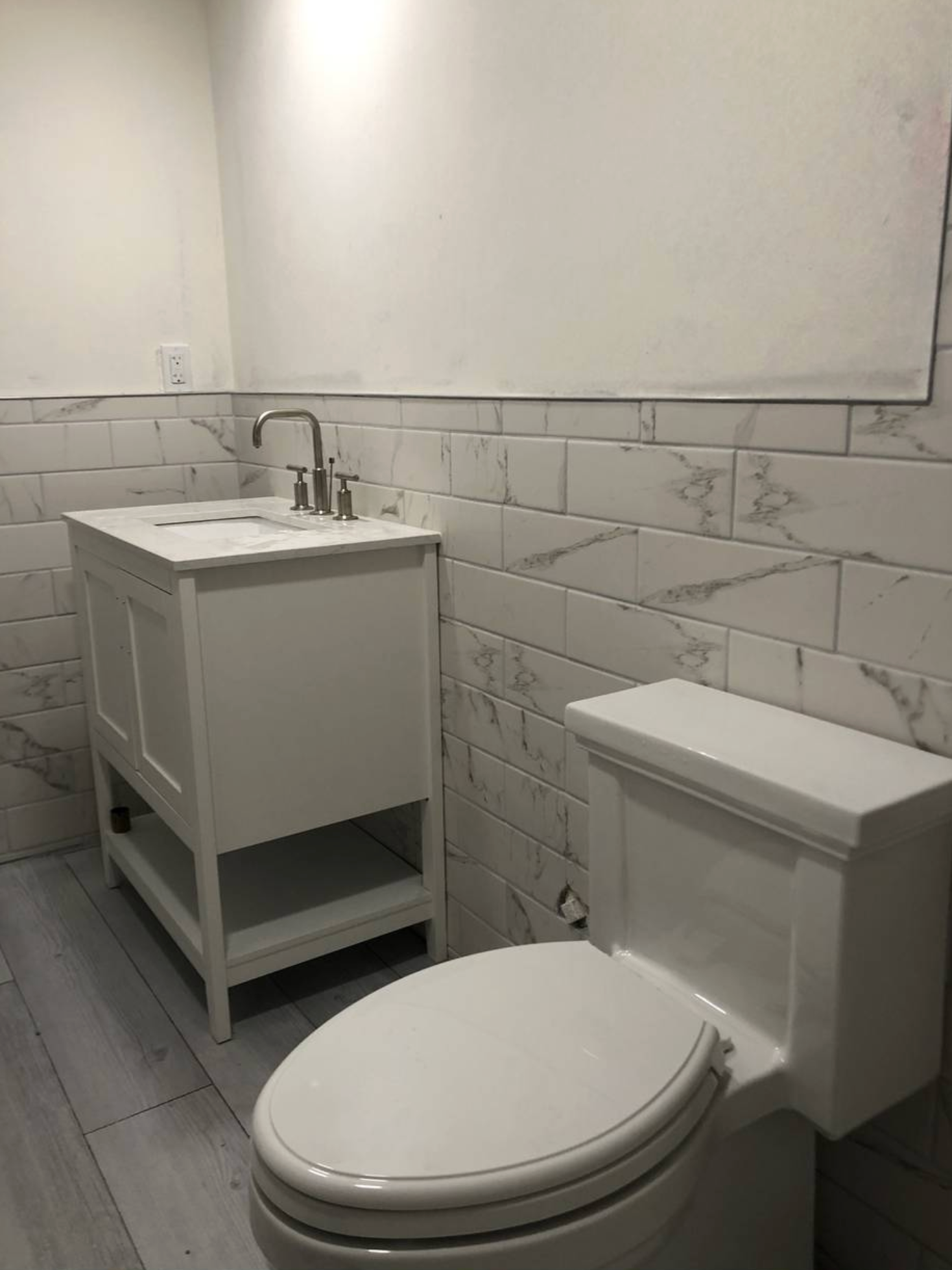 A bathroom with a toilet , sink and vanity.
