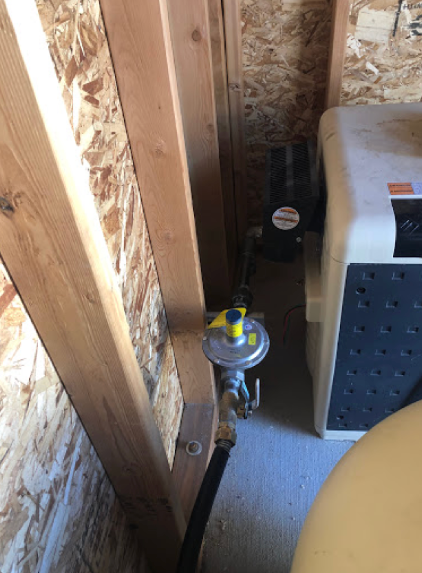 A gas valve is attached to a wall next to a heater.