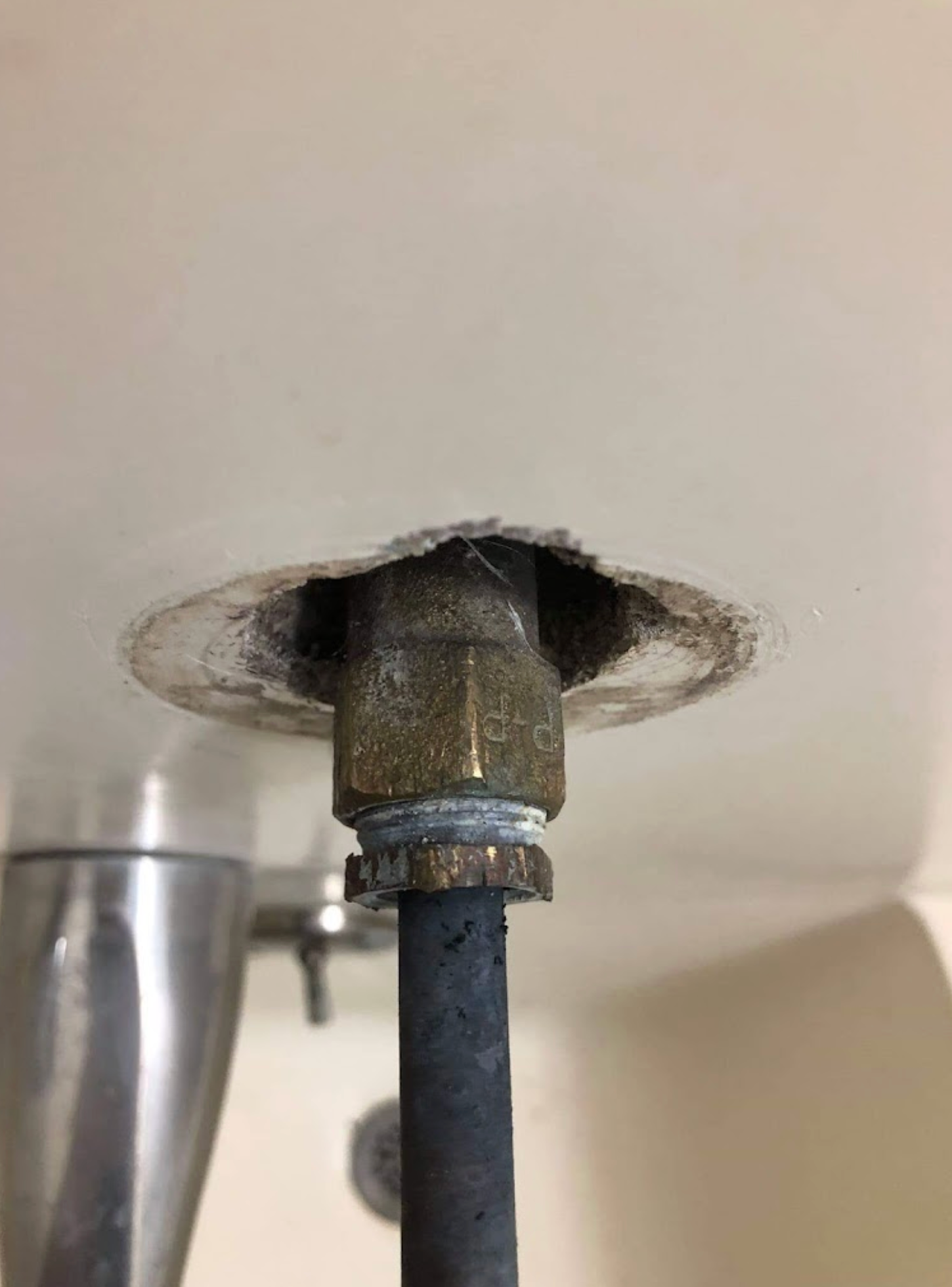 A close up of a pipe under a sink in a bathroom.
