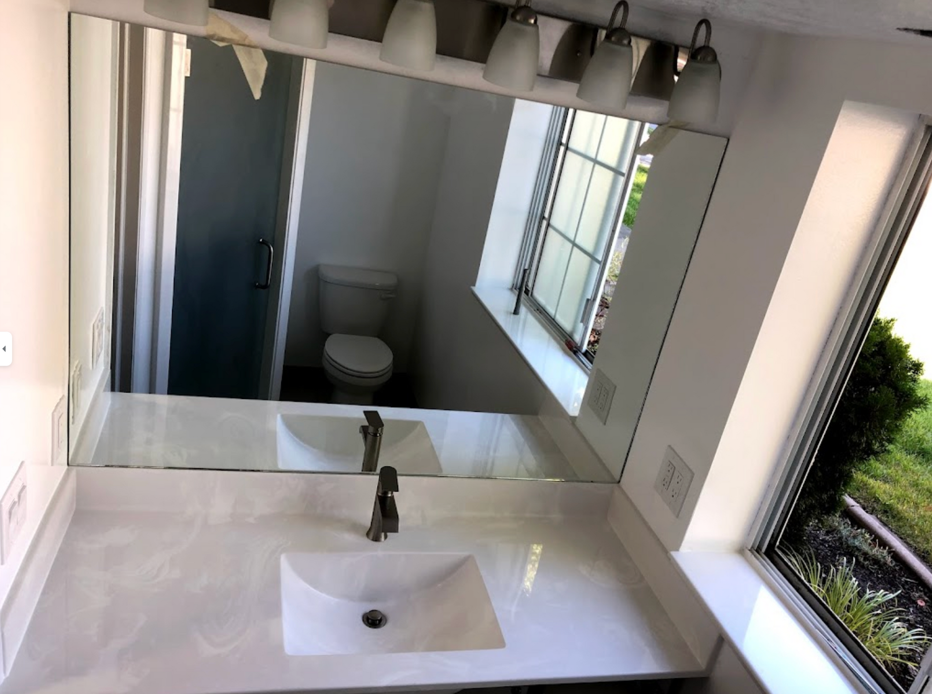 A bathroom with a sink a toilet and a large mirror