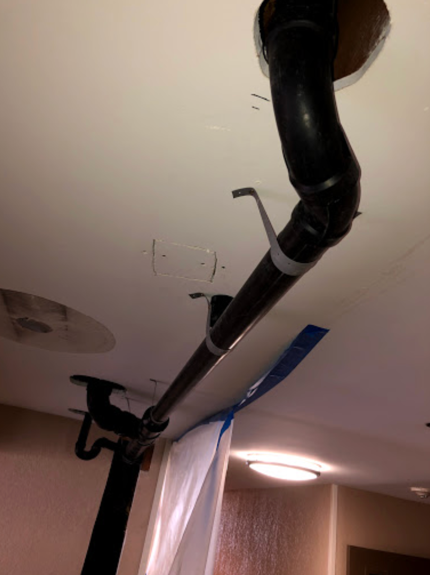 A black pipe is hanging from the ceiling in a room