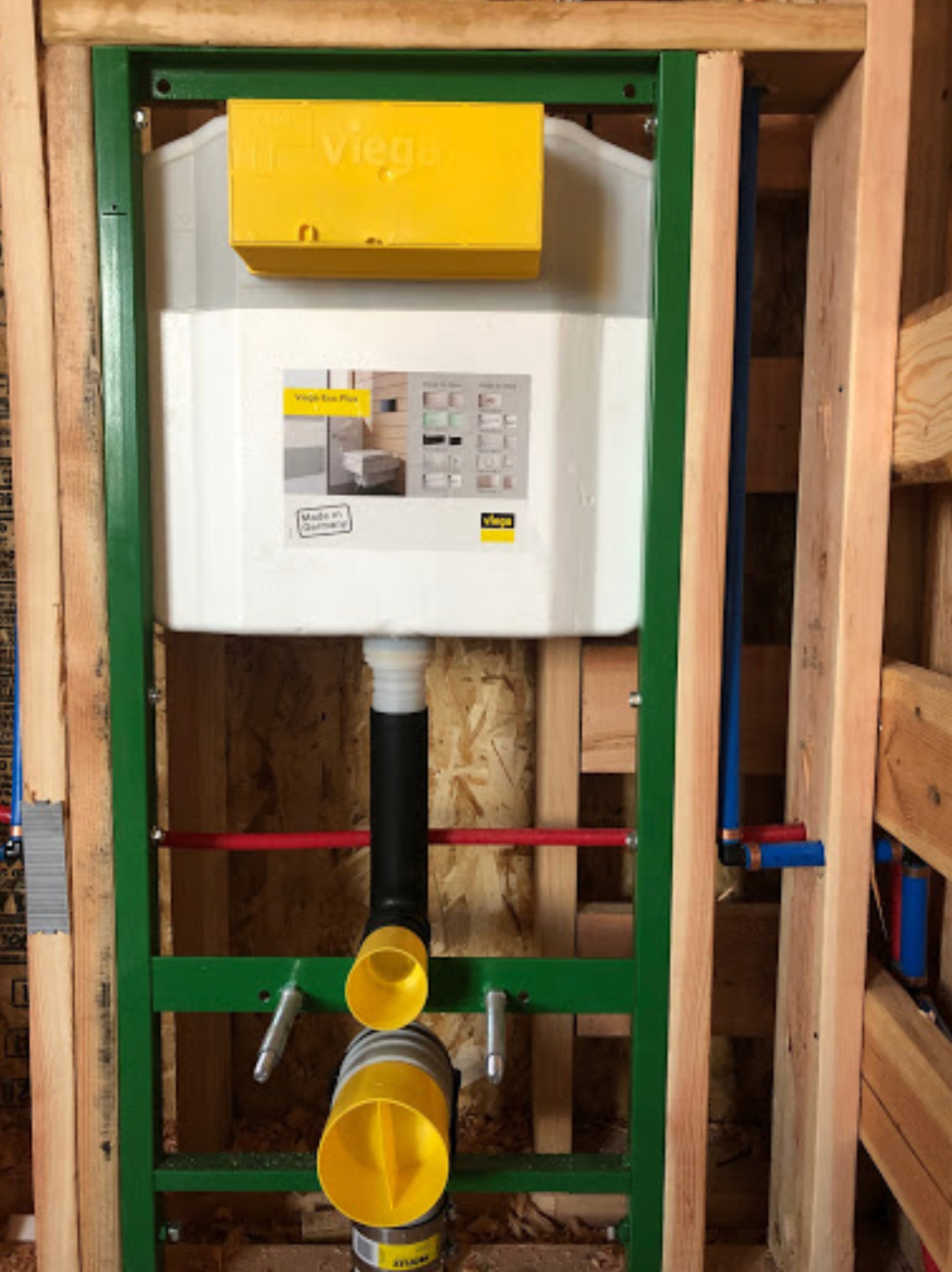 A wall mounted toilet with a yellow box on top of it