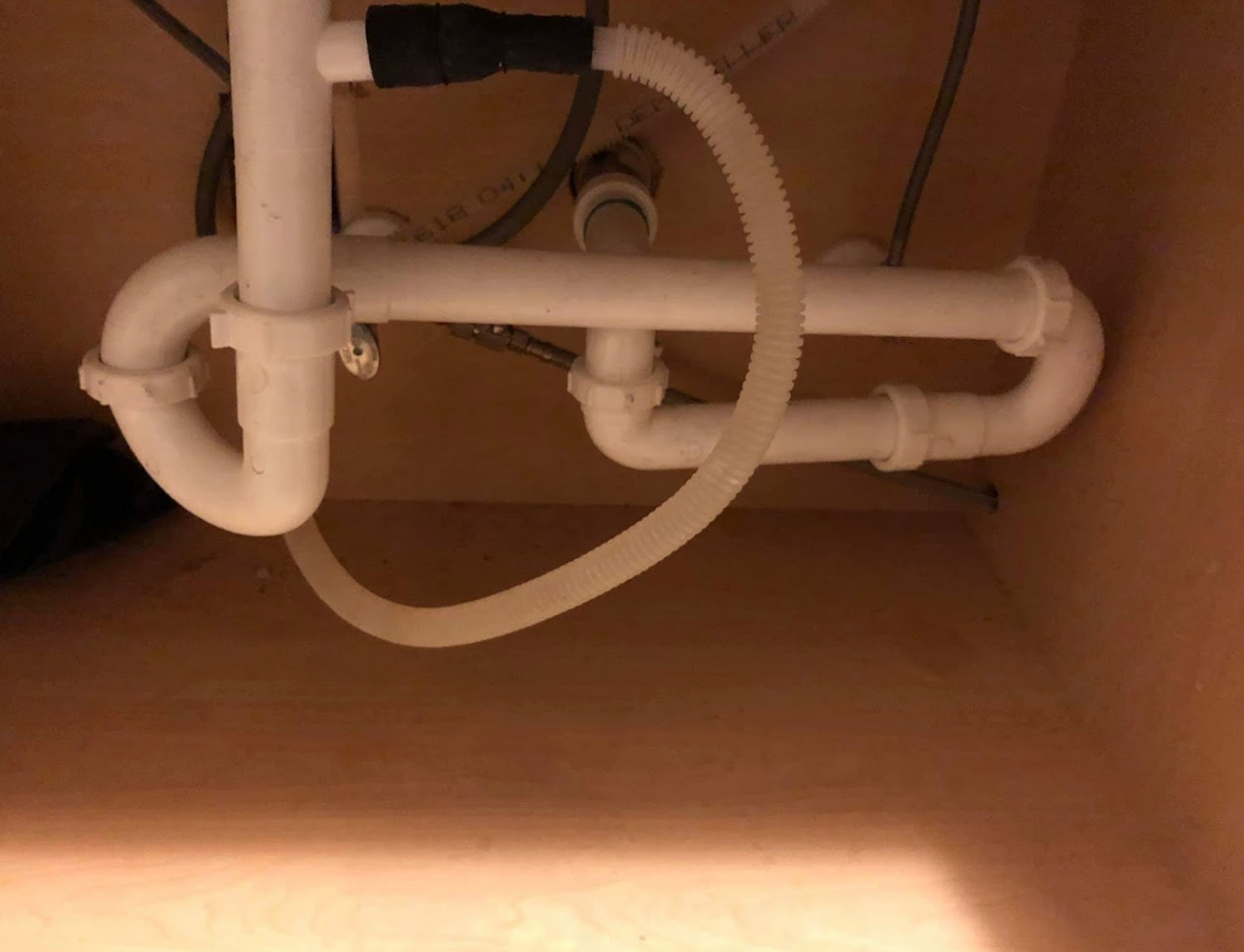 A close up of a sink pipe in a cabinet.