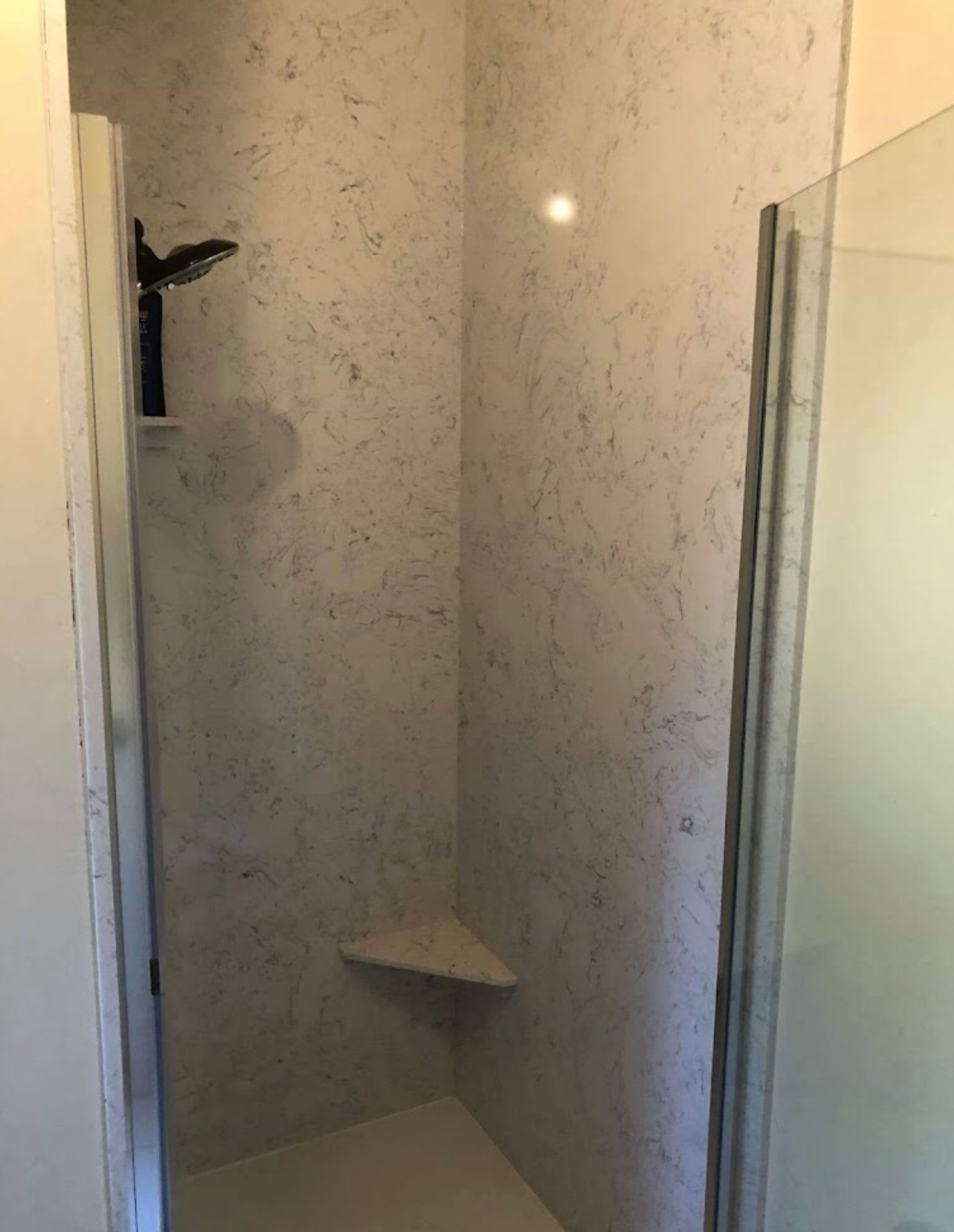 A bathroom with a walk in shower and a glass door.