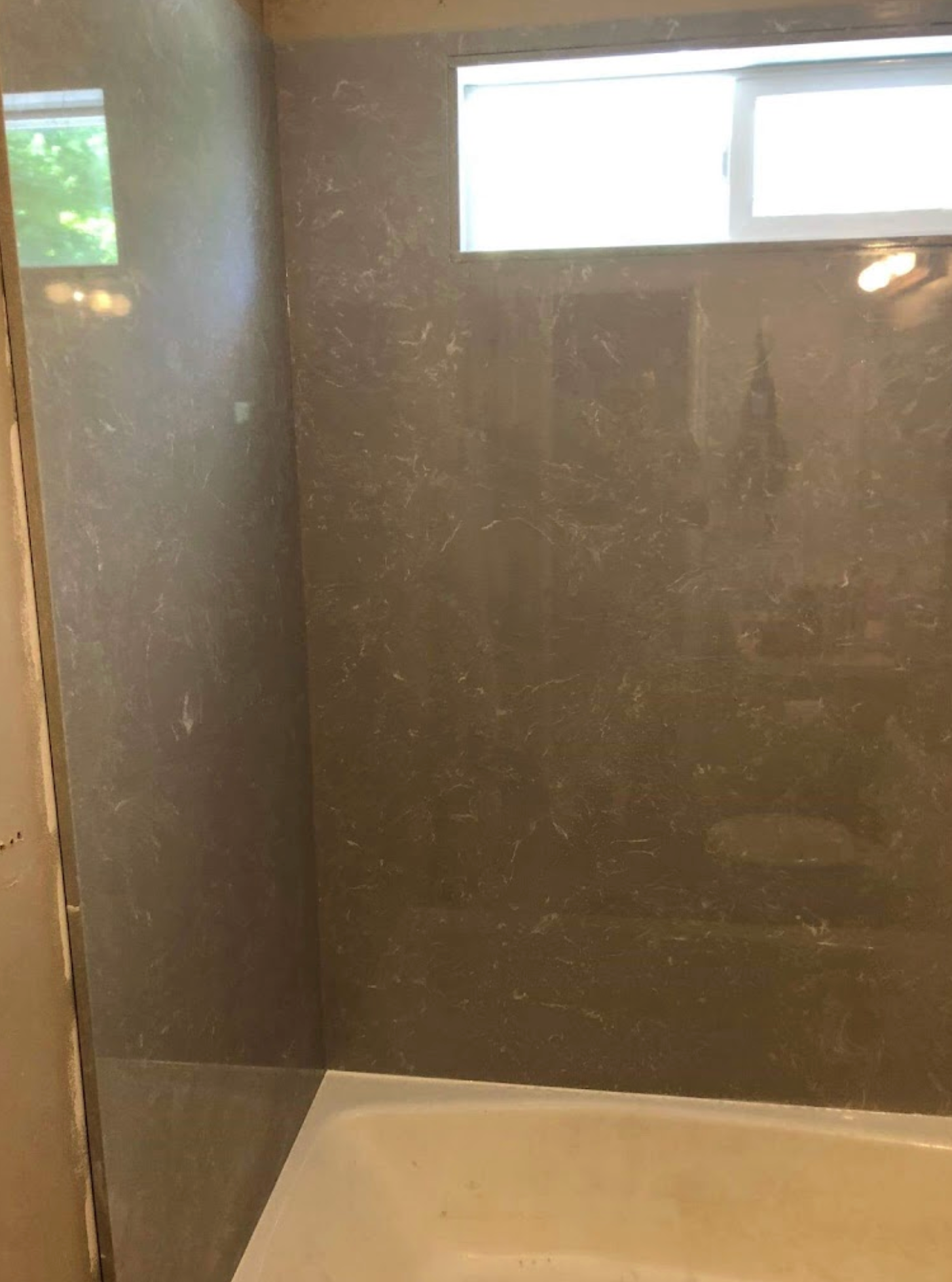 A bathroom with a bathtub and a shower stall with a window.