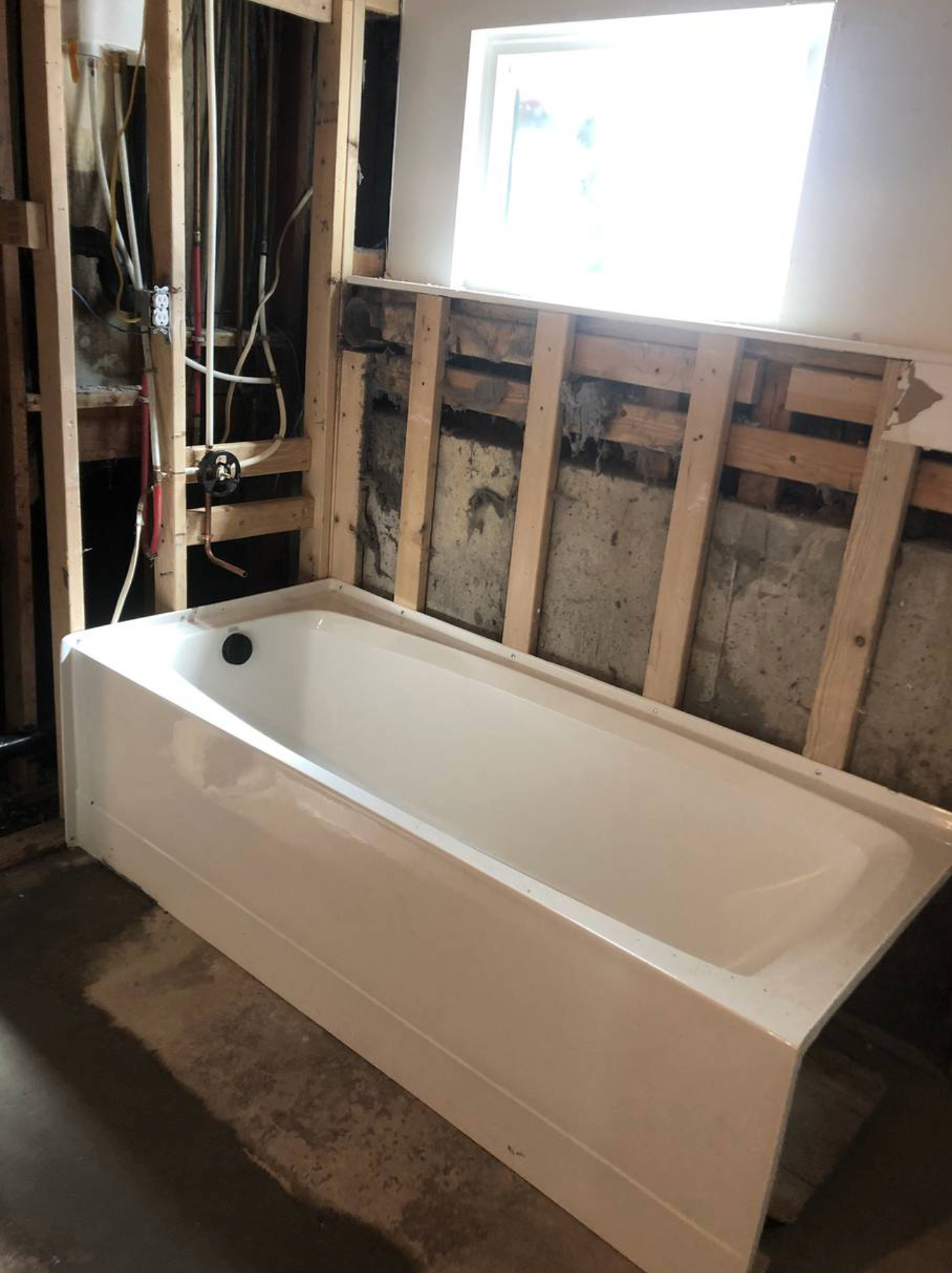A bathtub is sitting in a bathroom under construction.