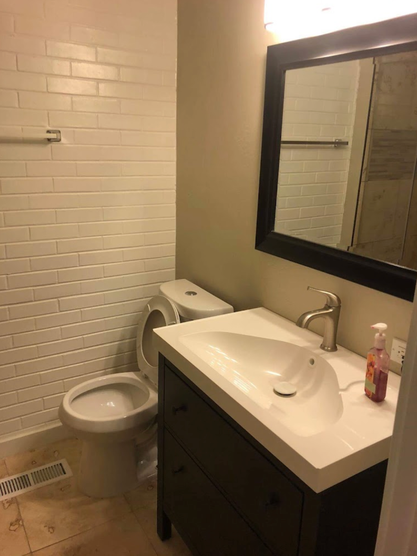 A bathroom with a toilet , sink and mirror