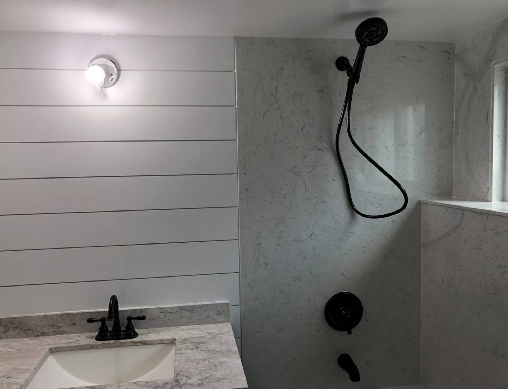 A bathroom with a sink and a shower with a black shower head.