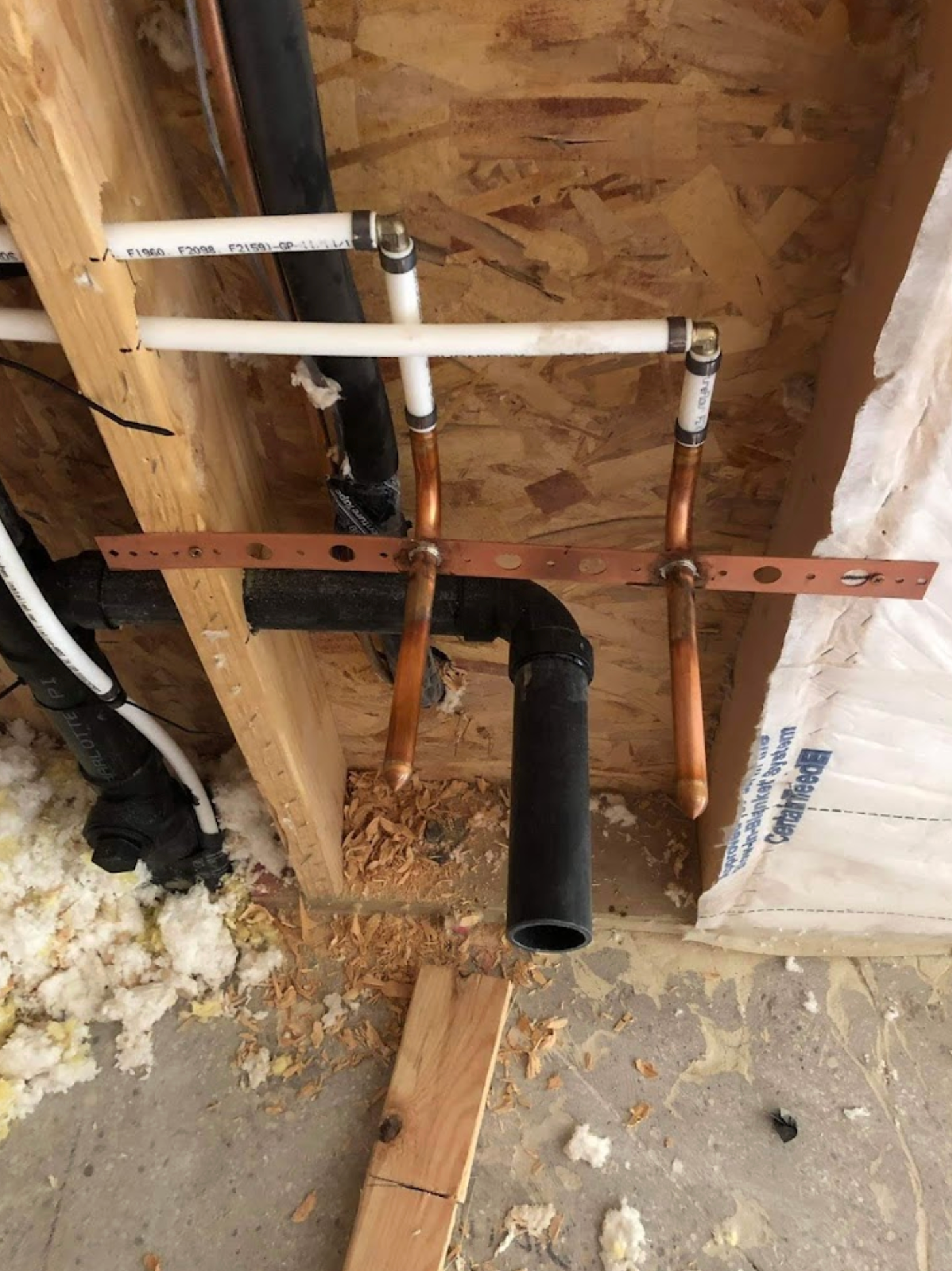 Copper pipes are being installed in a wooden wall.