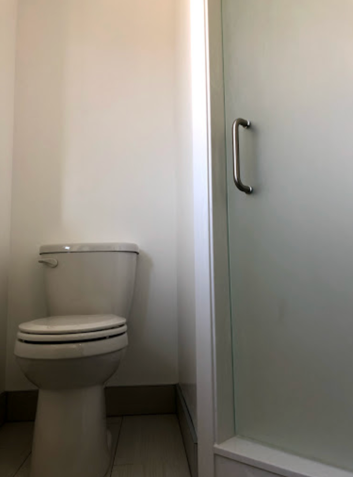 A bathroom with a toilet and a shower stall