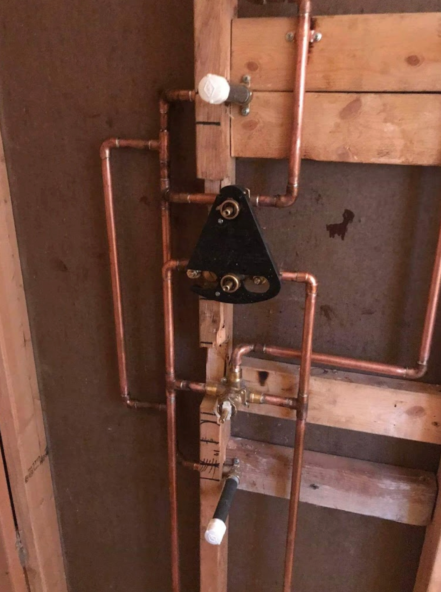 A bunch of copper pipes are hanging from a wooden wall.