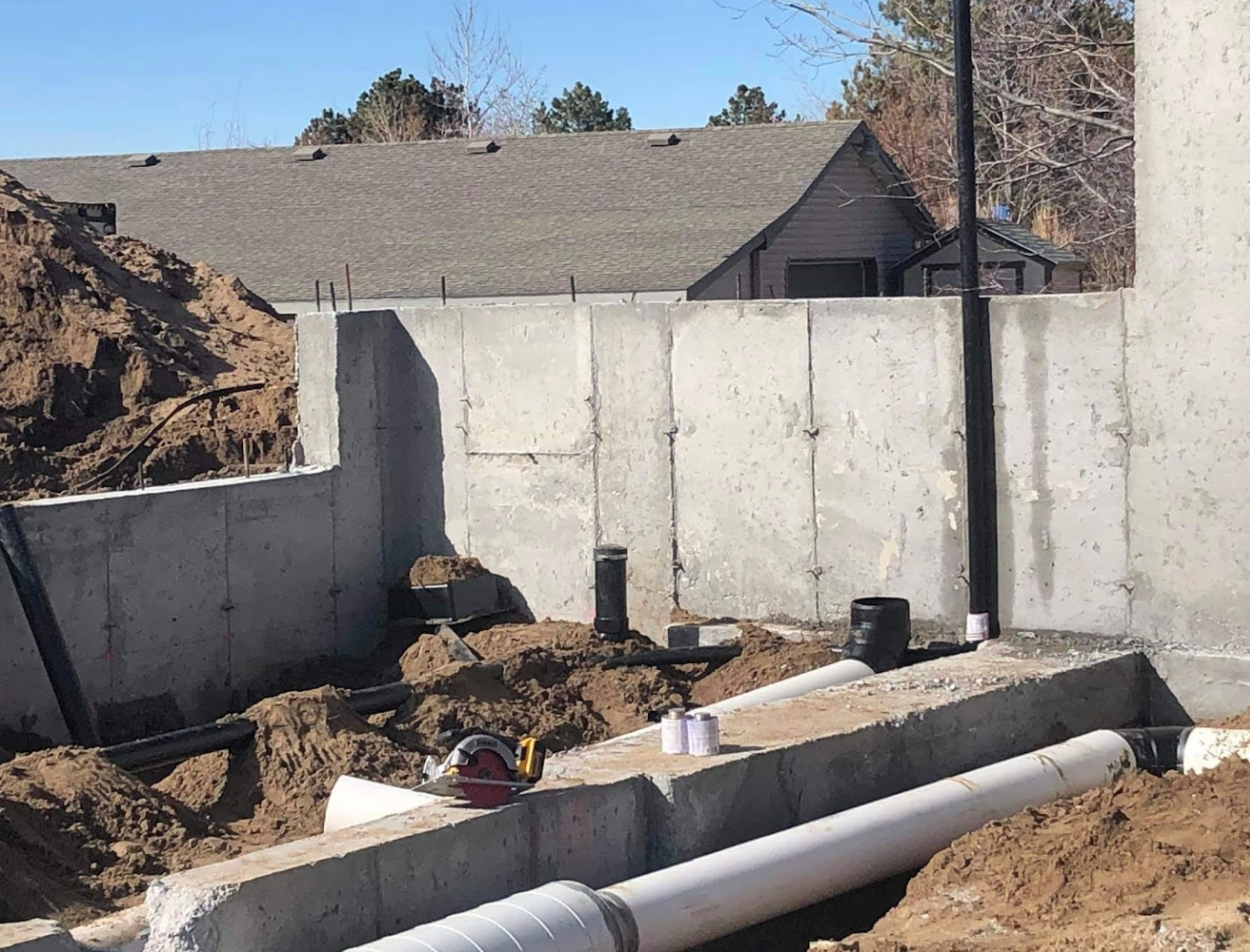 A concrete wall is being built next to a pile of dirt and pipes.