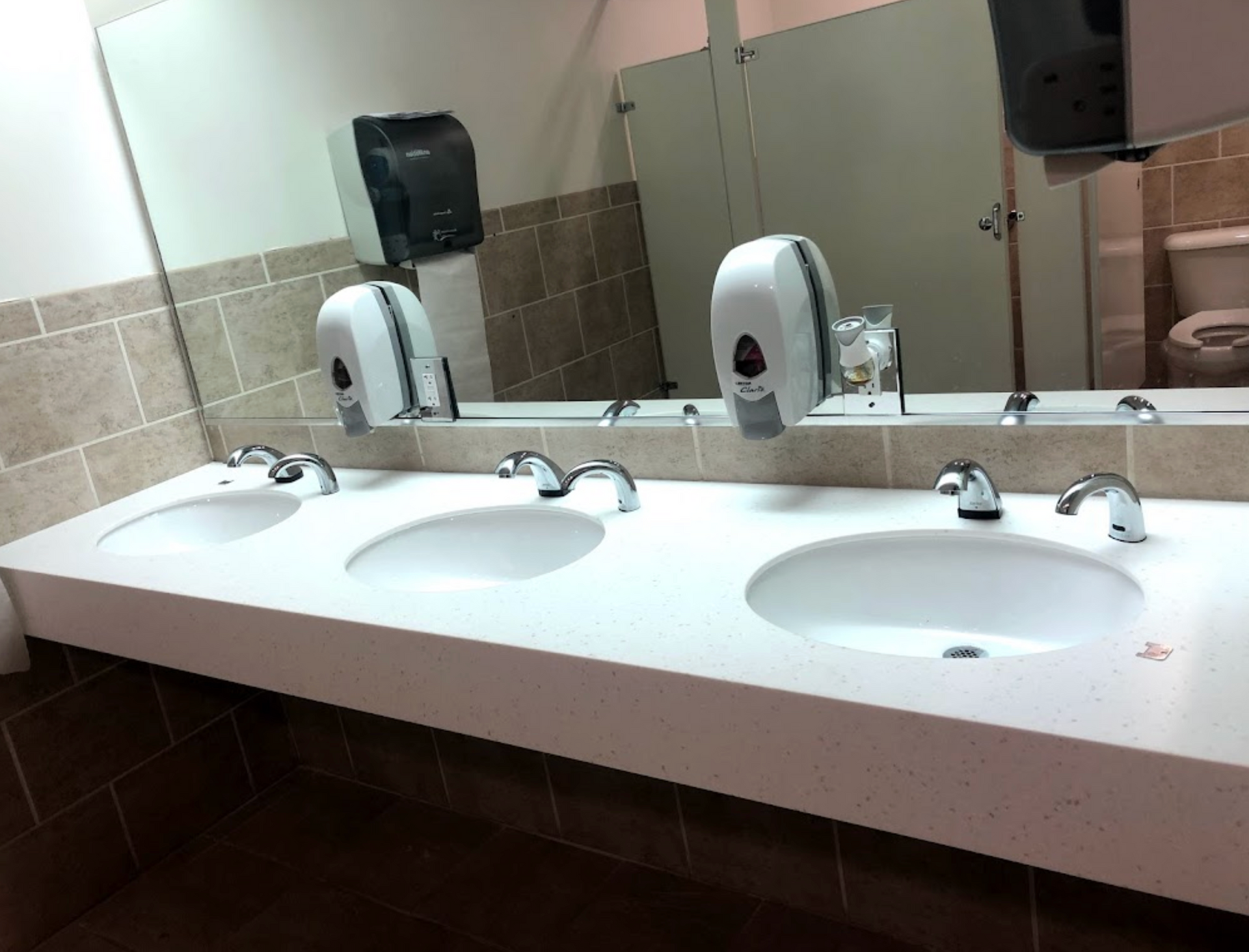 A bathroom with three sinks and a toilet
