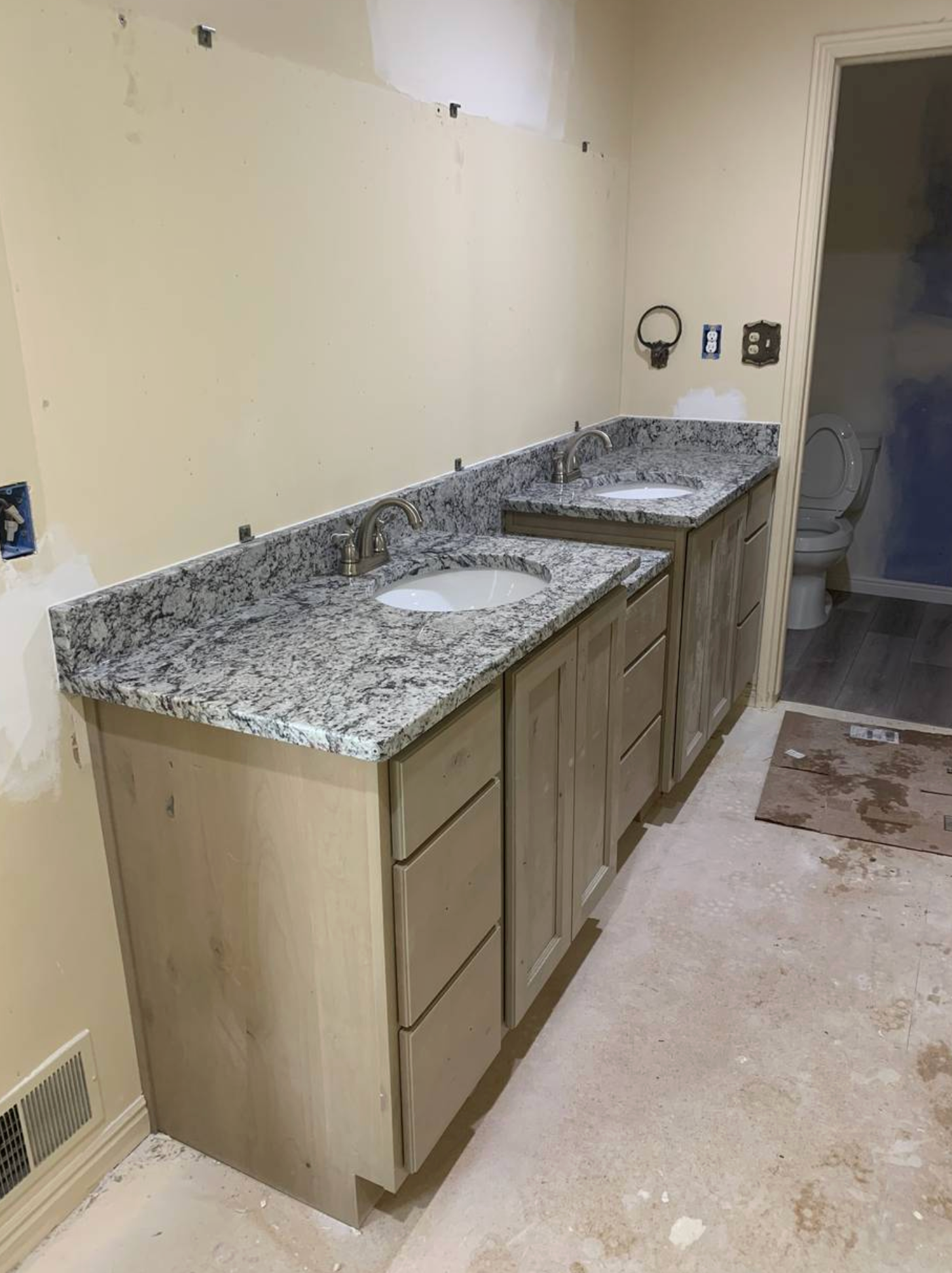 A bathroom with two sinks and a toilet under construction.