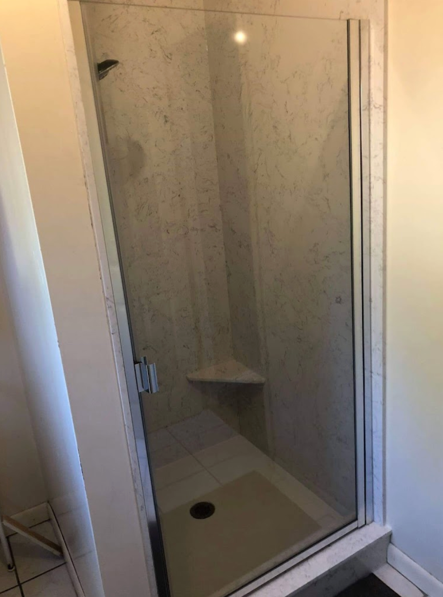 A bathroom with a walk in shower with a glass door.